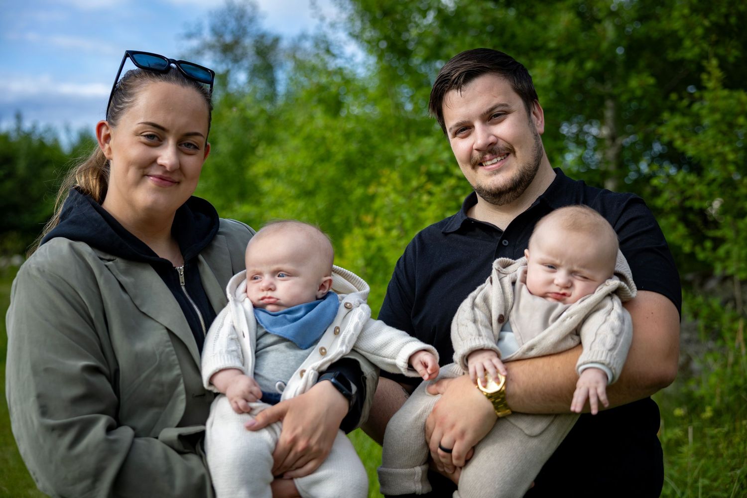 Familjesammankomst utomhus på solig dag med frodig grön bakgrund.
