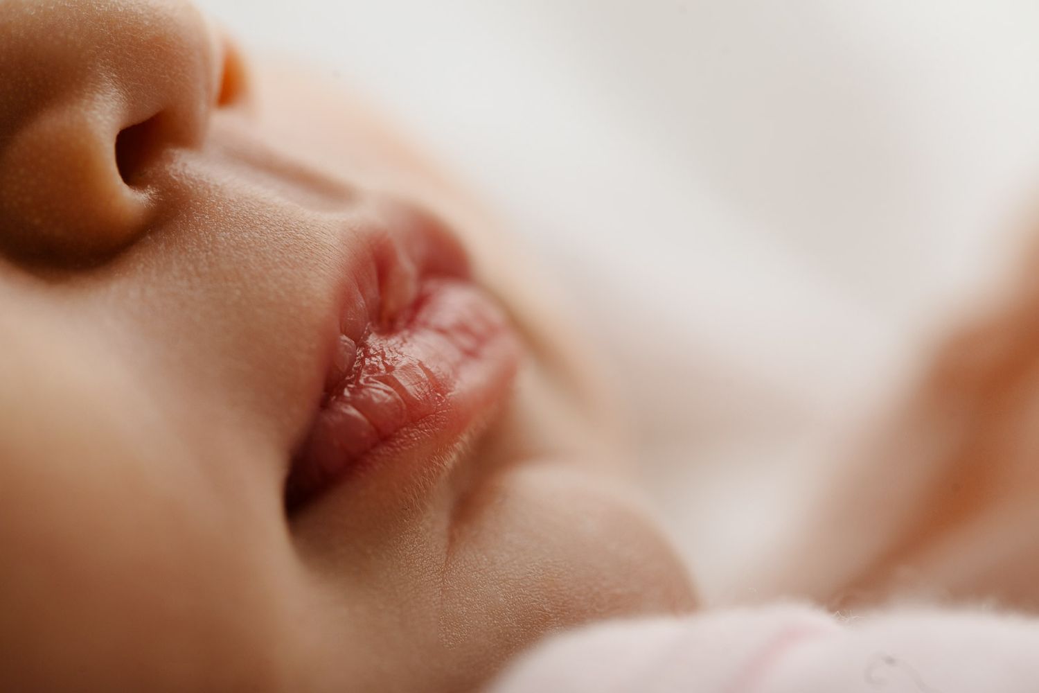 Extreme close-up of sleeping baby's features in soft natural light.