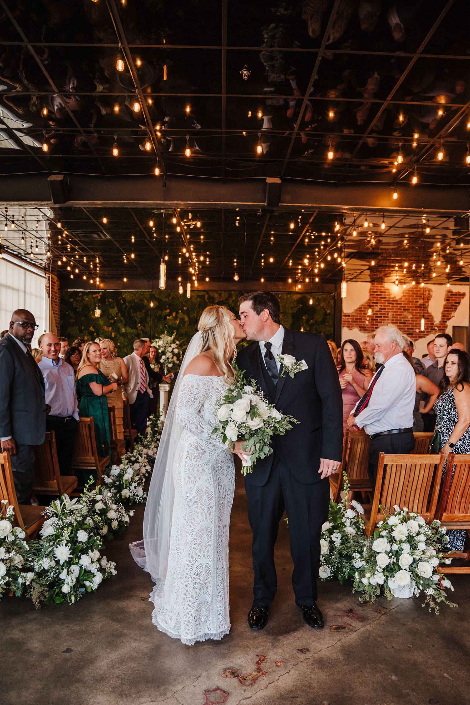 a bride and groom kissing at the end of the aisle at their wedding