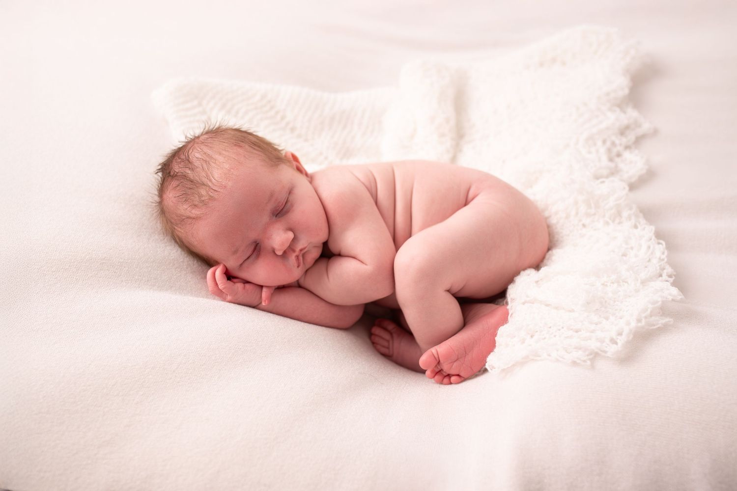 Artistic collection of soft black and white images showing a sleeping newborn baby on white blankets and lace.
