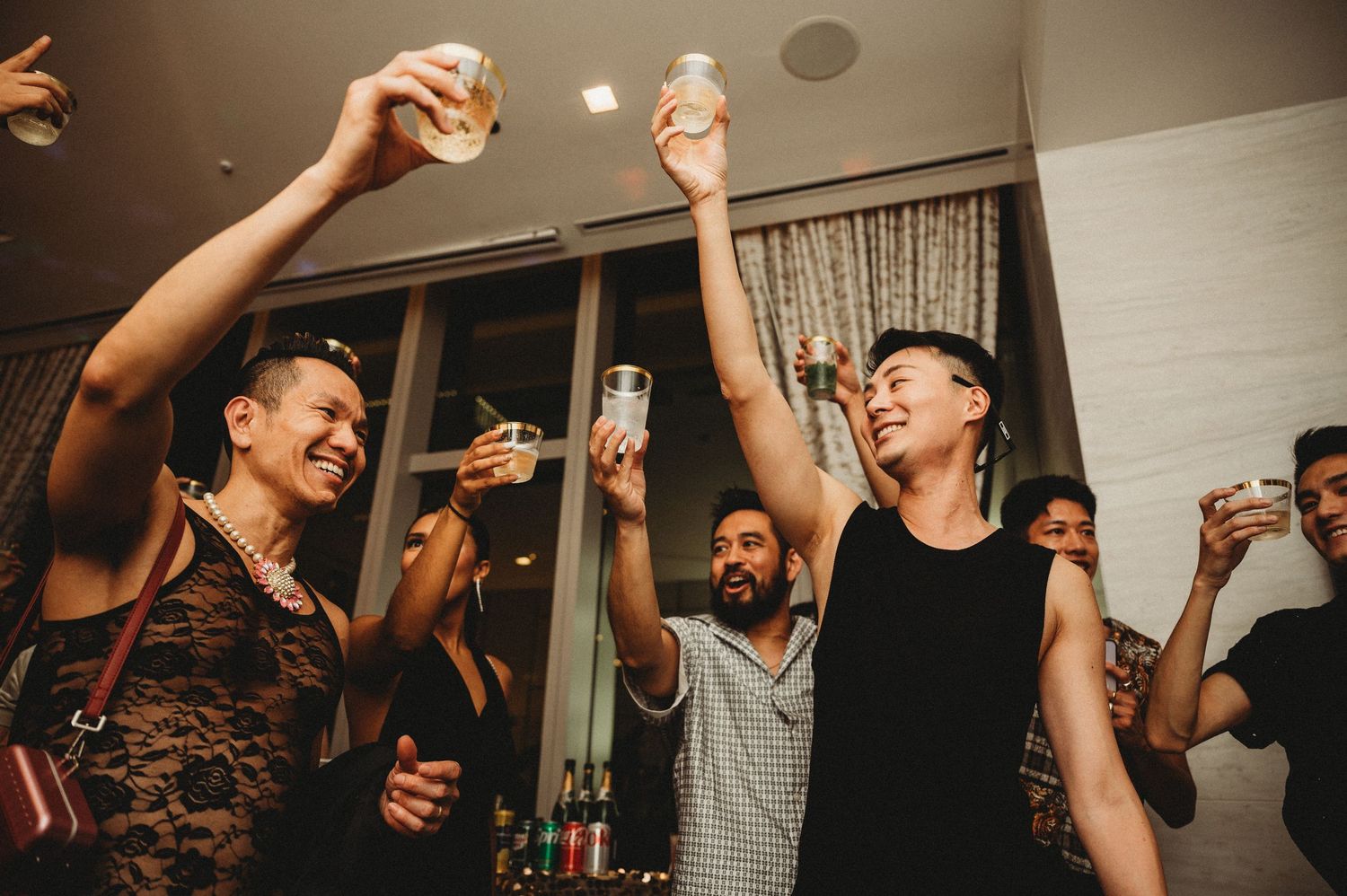 Group of friends celebrating and toasting drinks at a lively indoor party event.