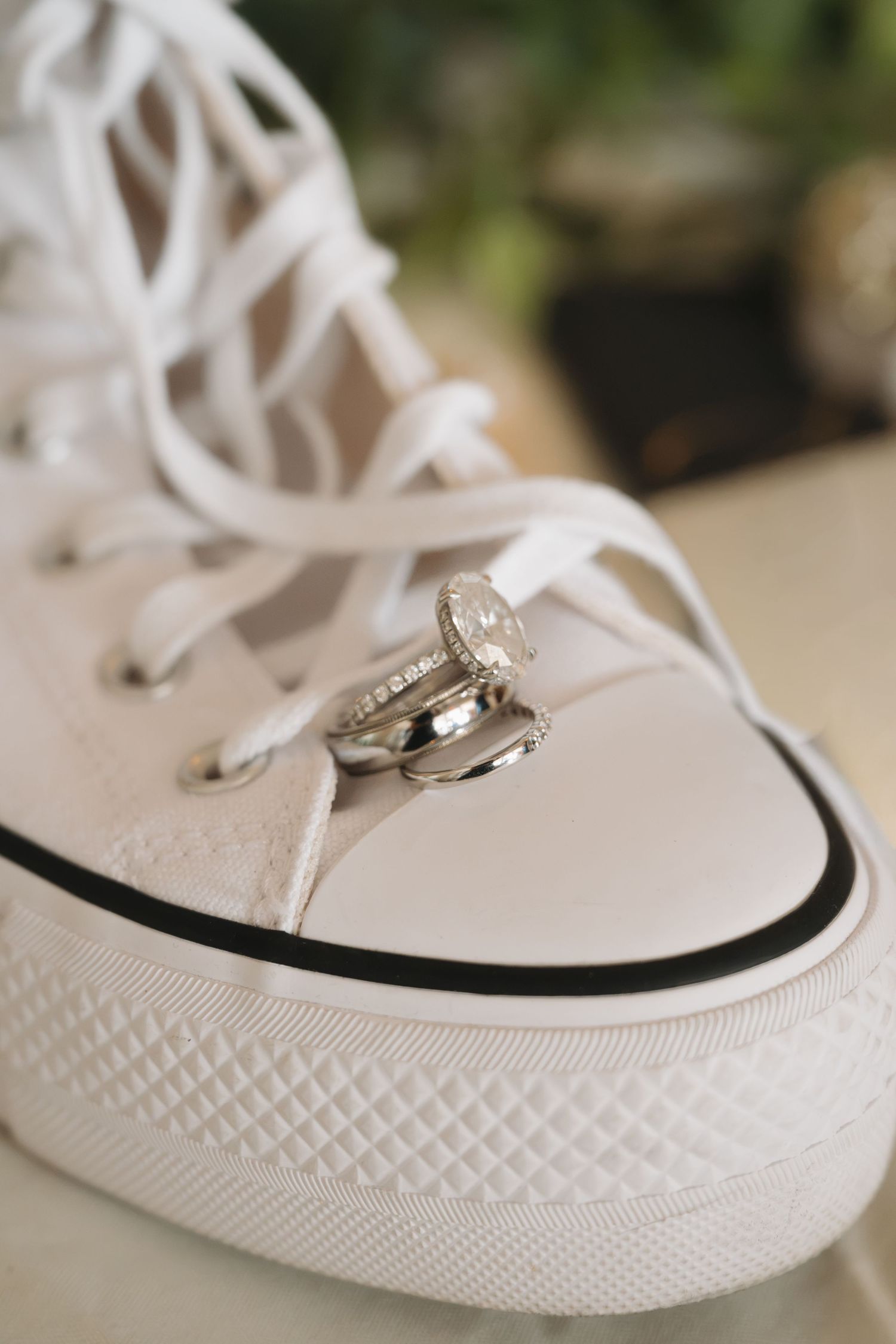 Wedding rings resting on a white Converse sneaker with white laces, symbolizing a casual bridal style.