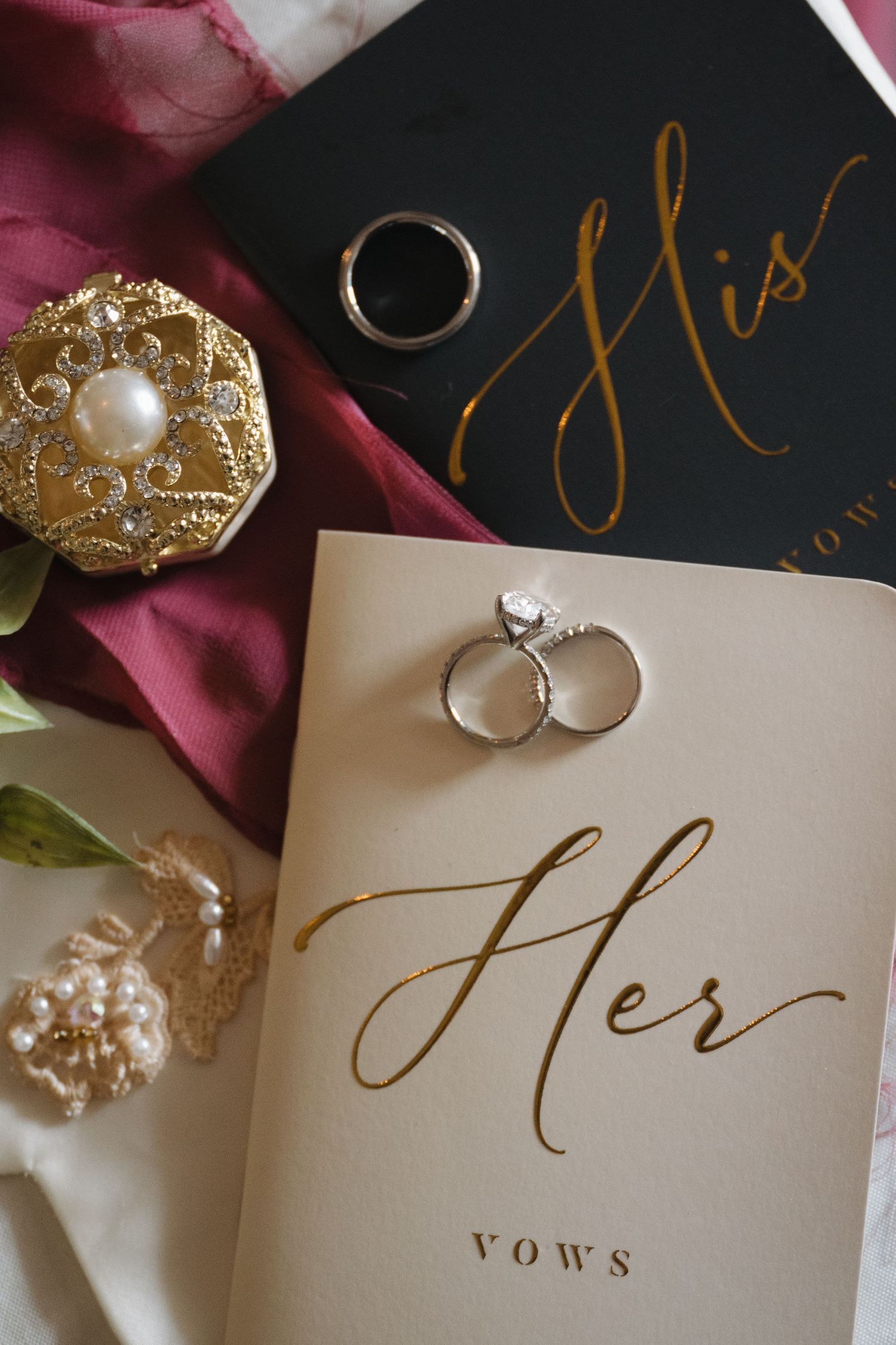 Wedding vow books labeled His and Her with diamond engagement ring, gold jewelry box, and pearl accessories.
