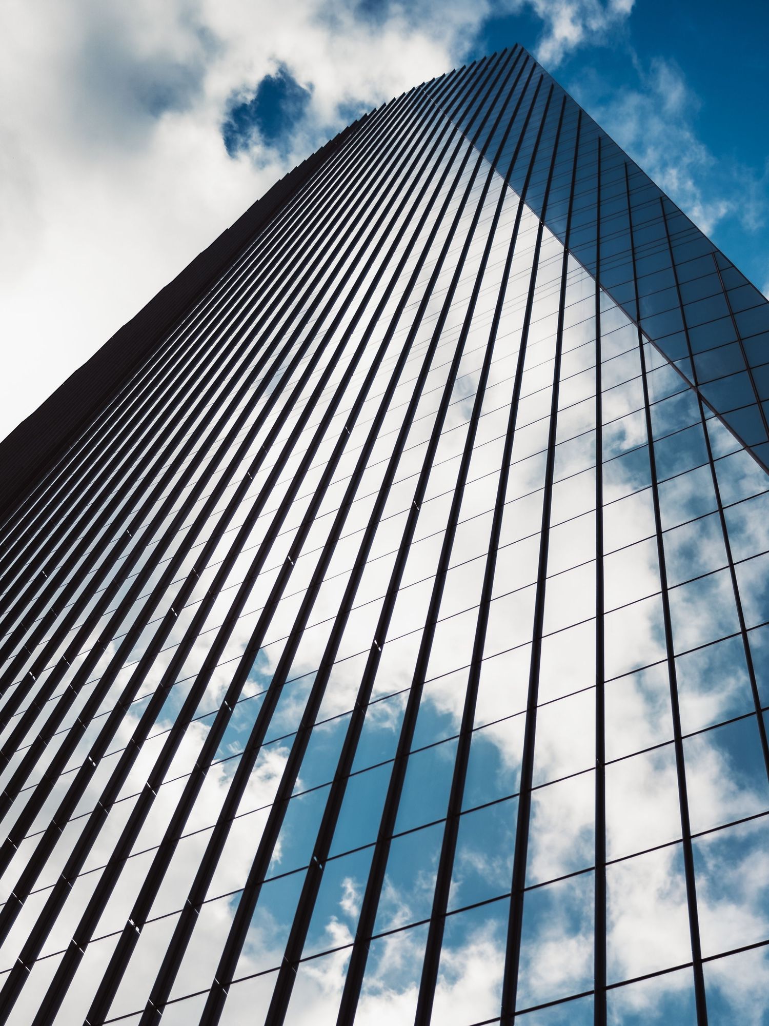 Glass office tower reflecting clouds and blue sky in downtown Austin