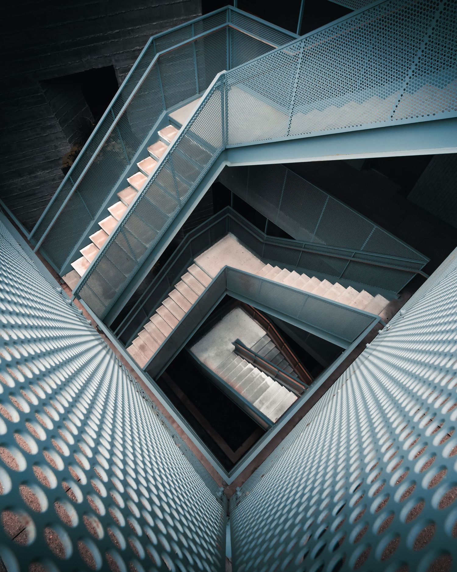 Looking down through repeating geometric levels of a modern staircase