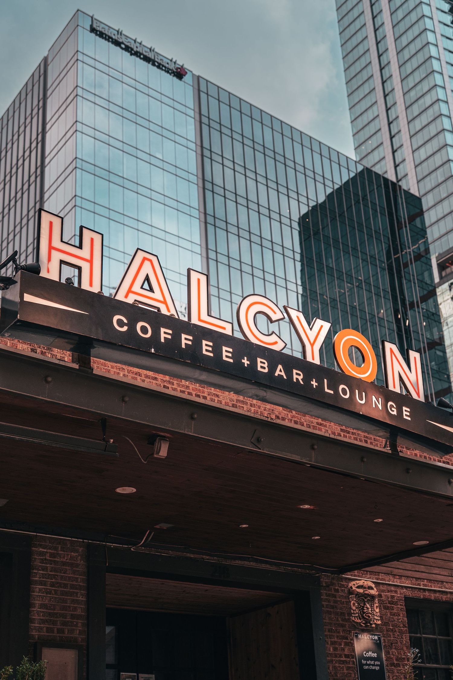 Exterior signage of Halcyon Coffee, Bar & Lounge surrounded by downtown Austin architecture