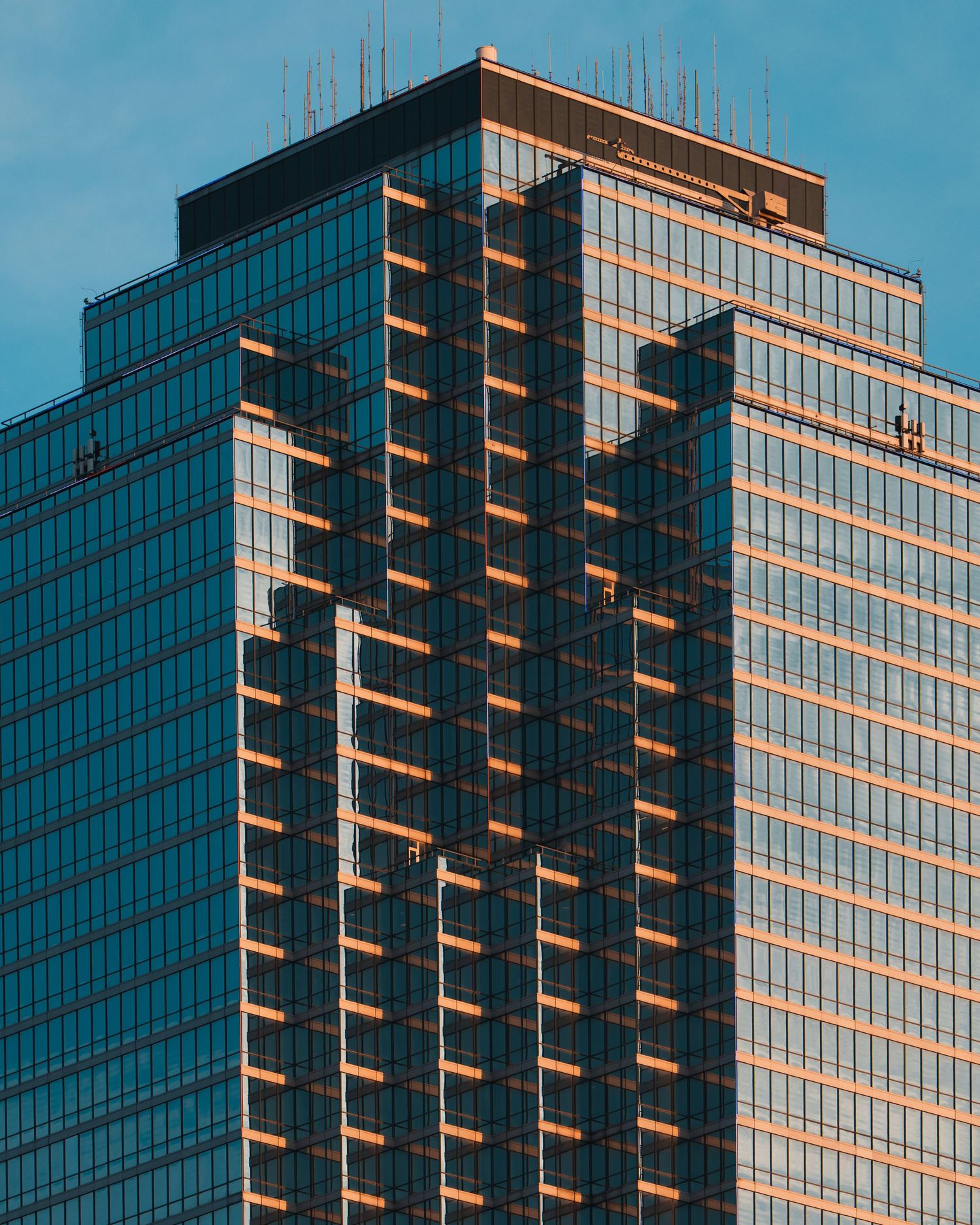 Modern glass skyscraper illuminated by warm evening light in downtown Dallas, Texas
