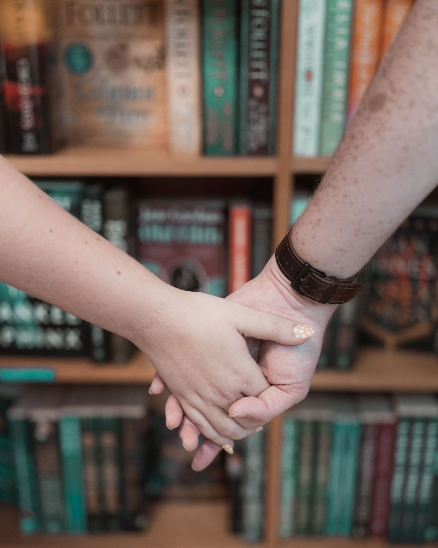 Couple holding hands between bookshelves at BookPeople in Austin, Texas