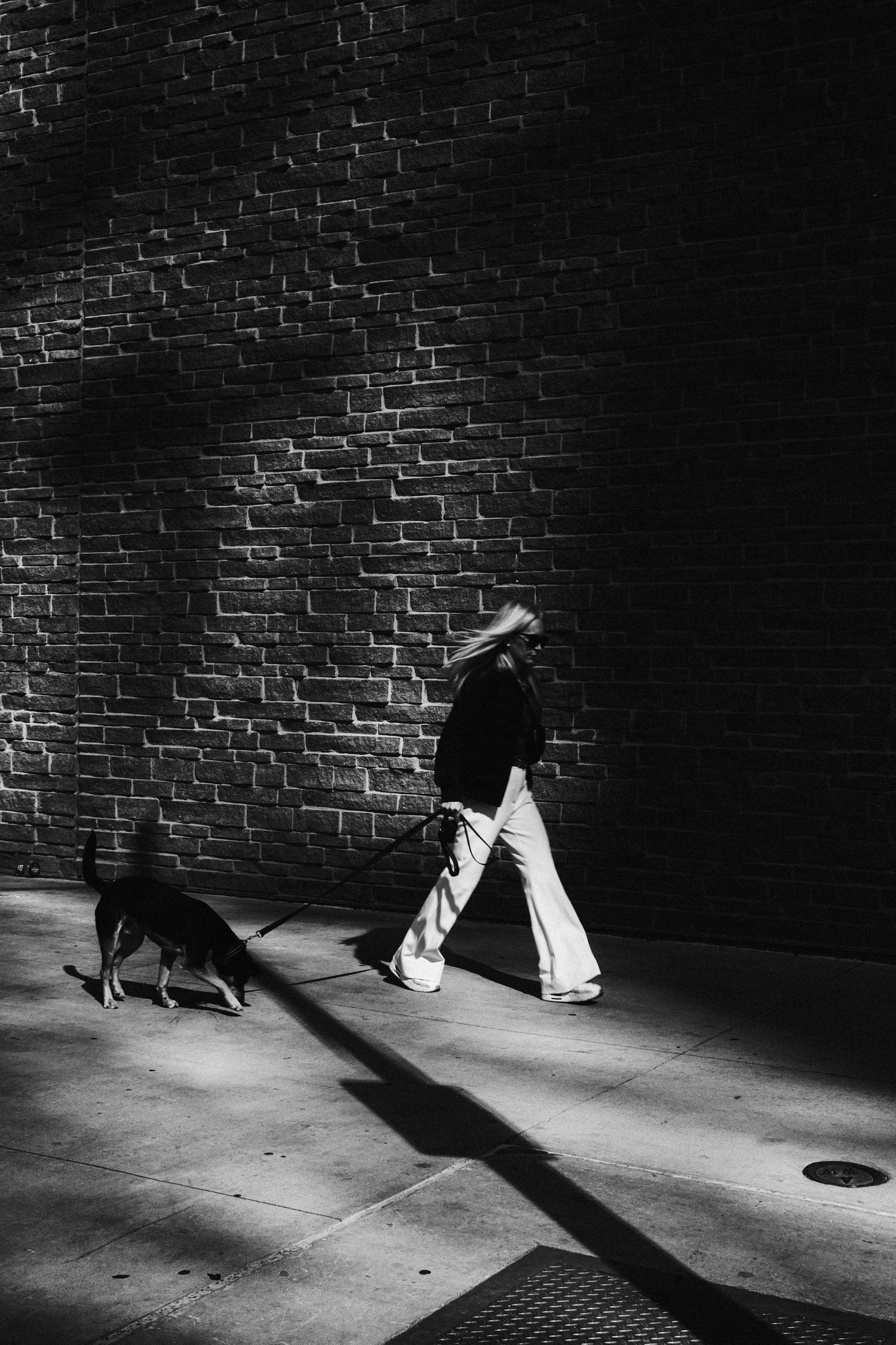 Black and white candid street photograph of a pedestrian in dramatic light in downtown Austin, Texas