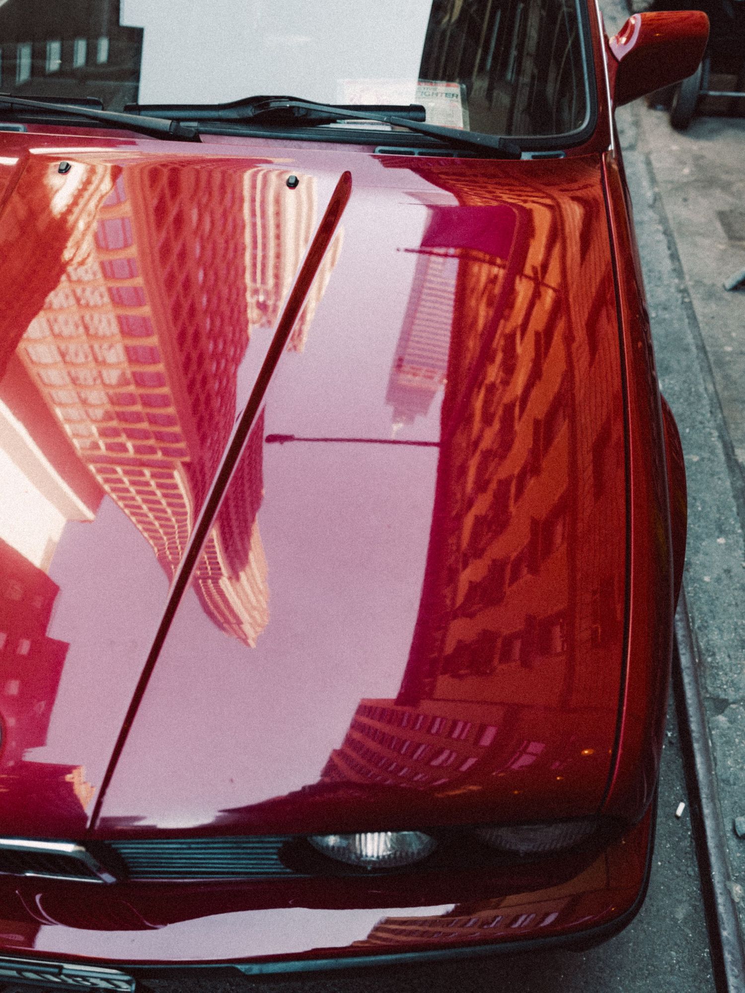 Red BMW reflecting Manhattan architecture on its hood in New York City