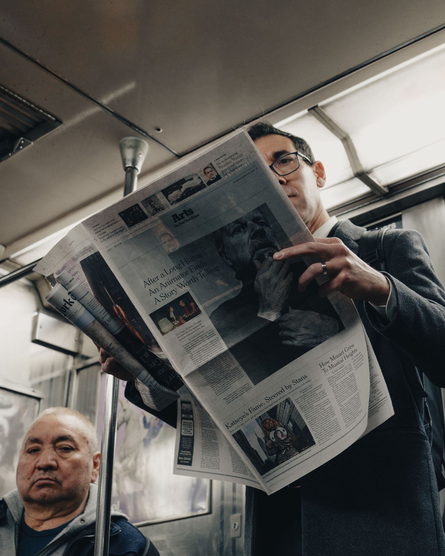 Passenger reading a newspaper while riding the New York City subway