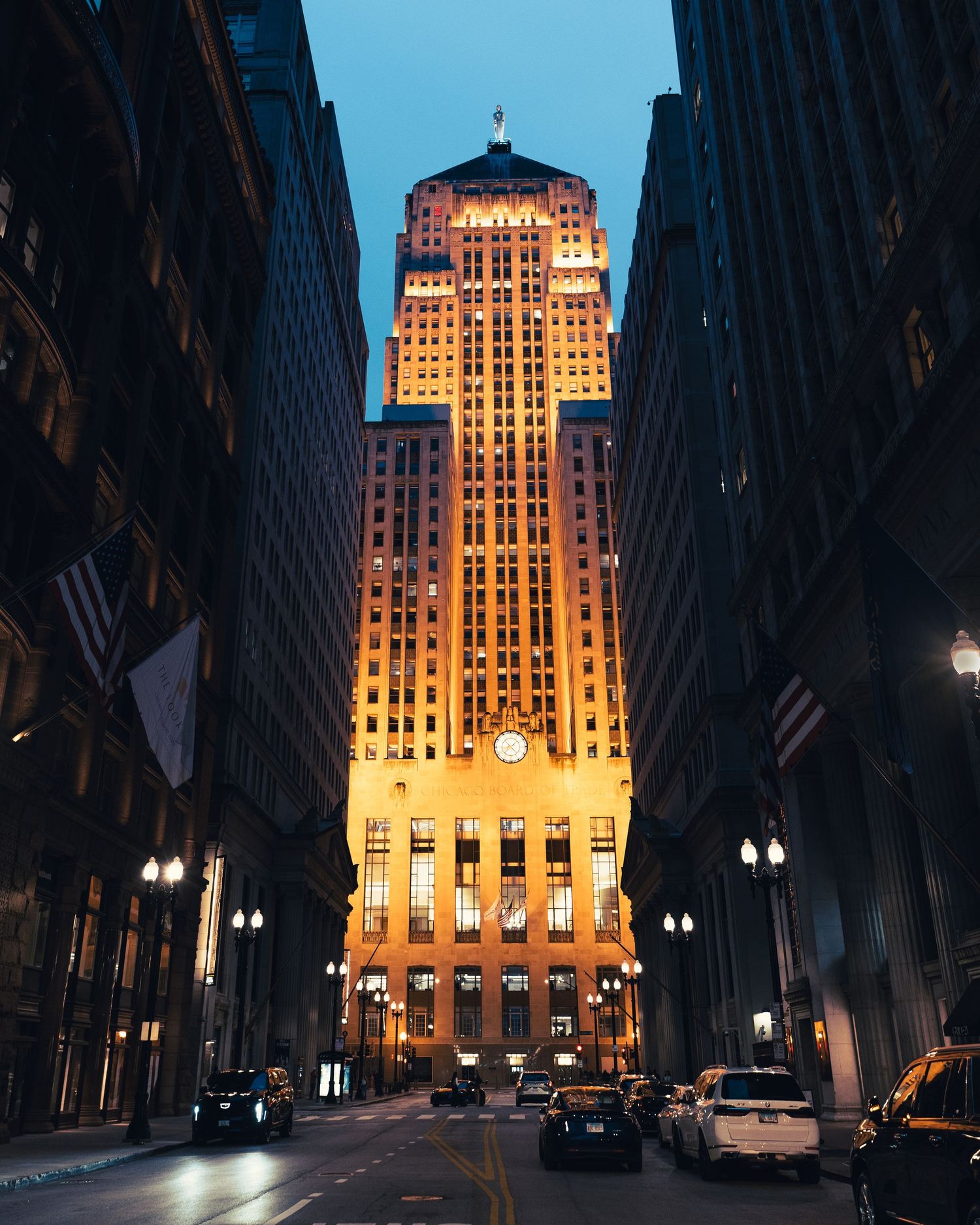 Illuminated historic skyscraper framed by buildings along a downtown Chicago street