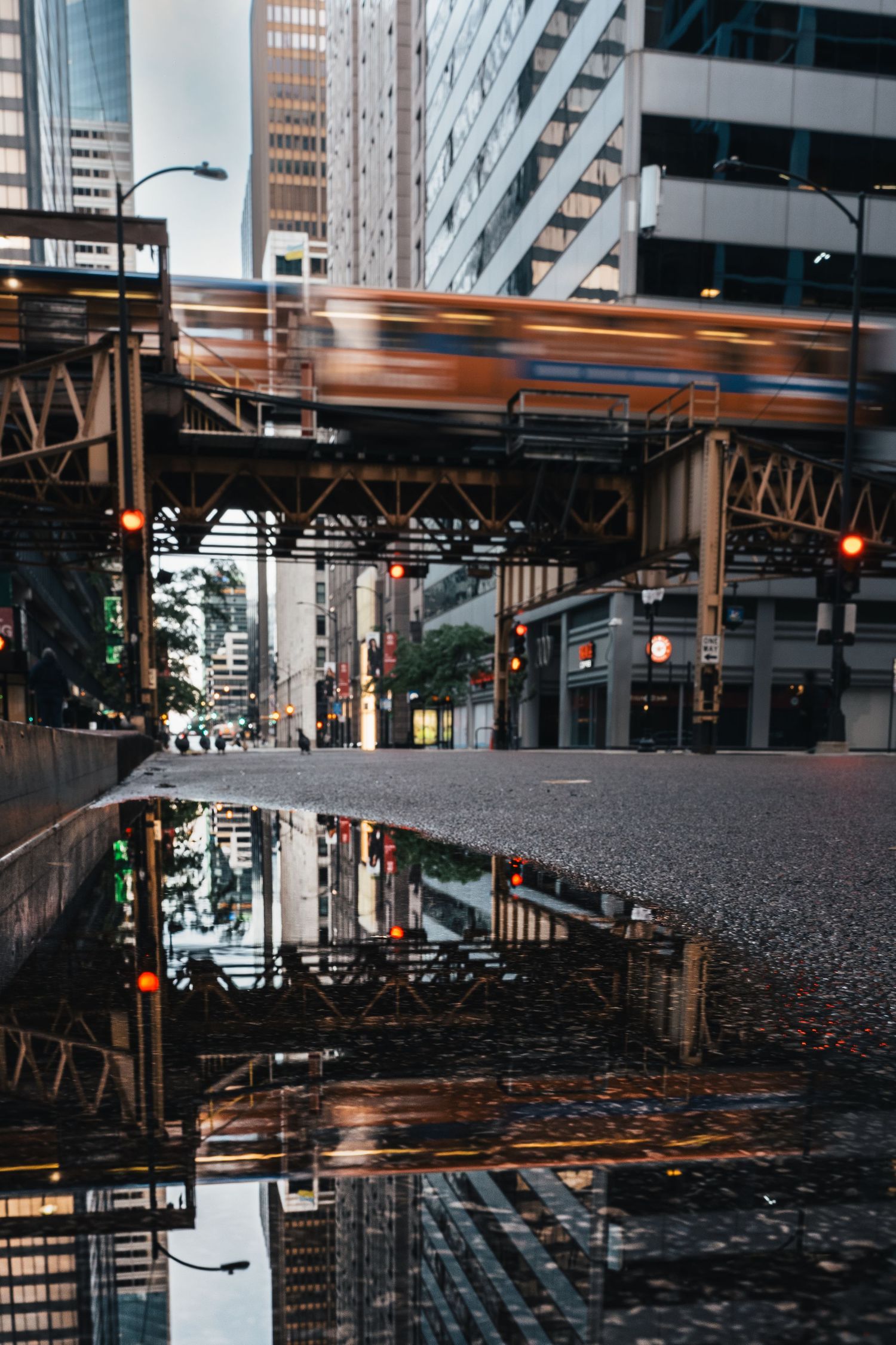 Chicago L train passing above a rain-soaked street with reflections in downtown Chicago