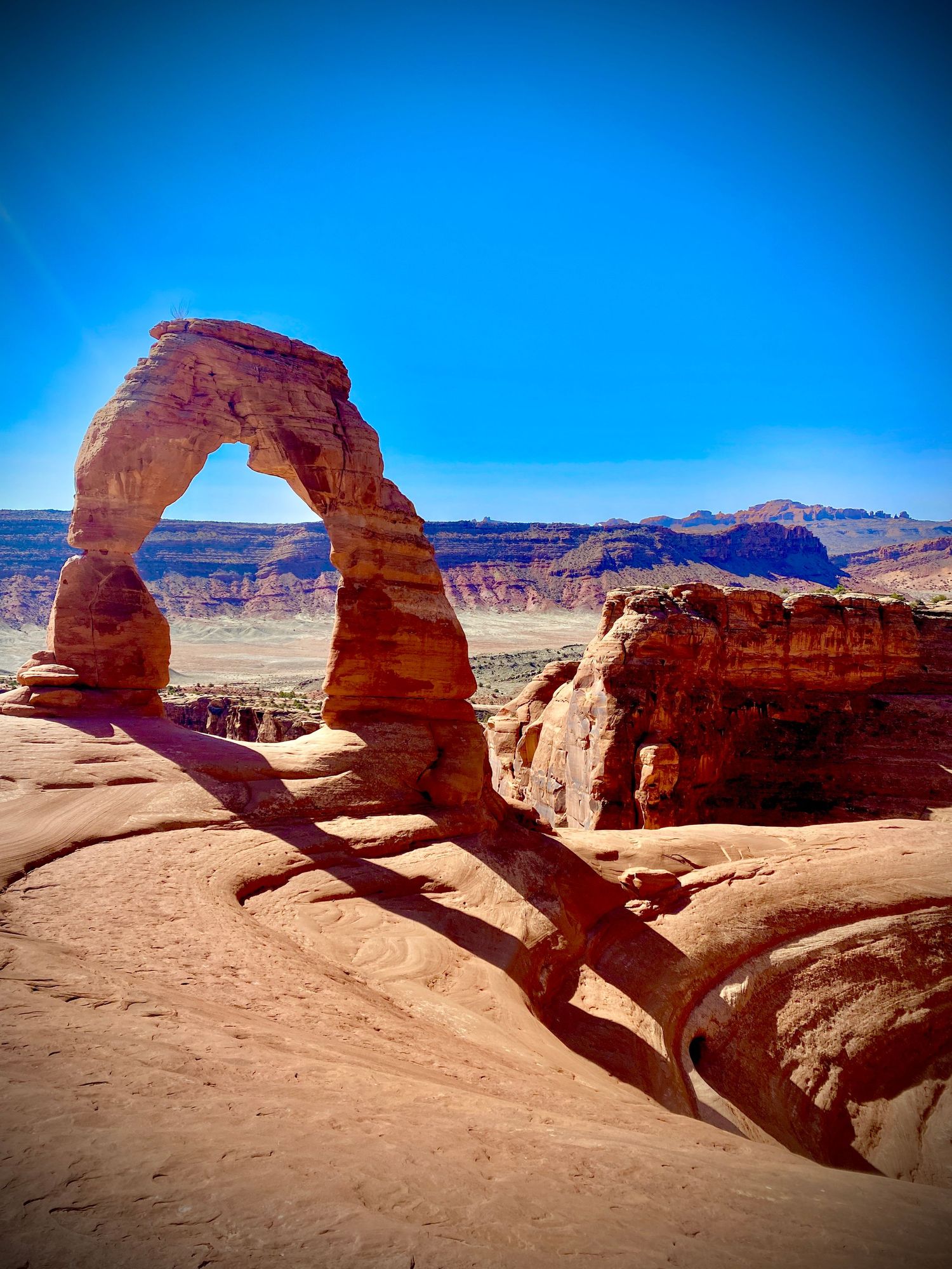 Delicate Arch at Arches National Park, Utah, framed against a vivid blue sky with red rock canyon views.