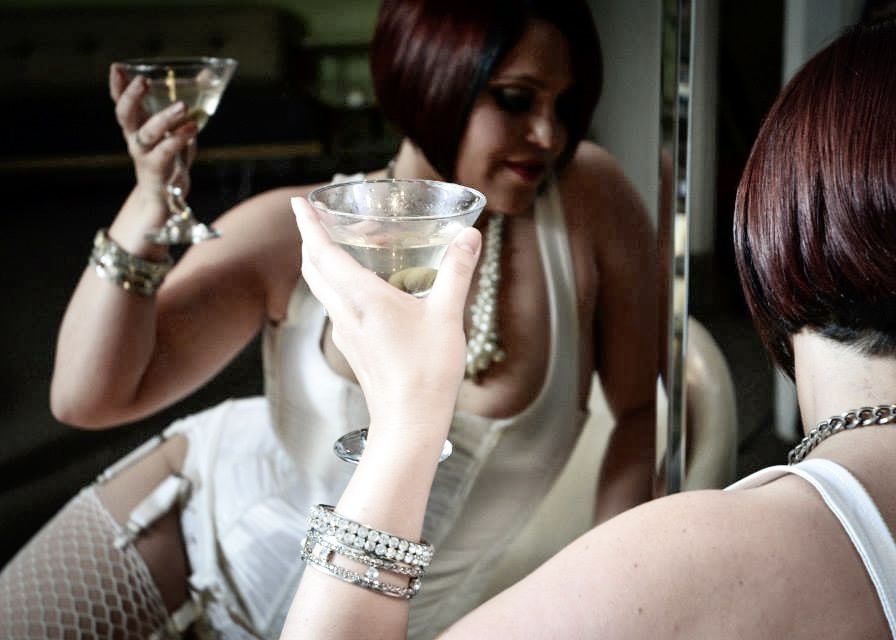 Two women with bracelets toasting with martini glasses at a glamorous event.