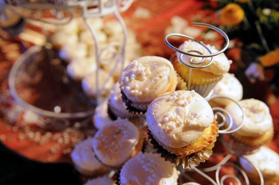 Elegant wedding cupcakes with white frosting displayed on a tiered stand with decorative silver rings.