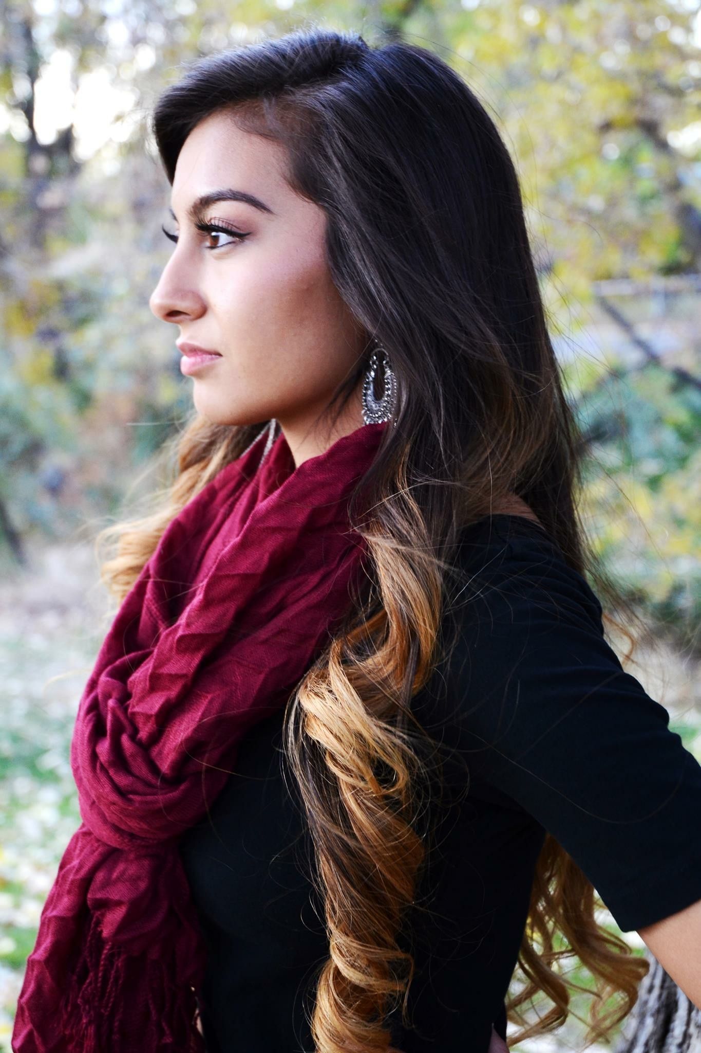 Young woman with long ombre hair wearing red scarf and black top in autumn outdoor setting.