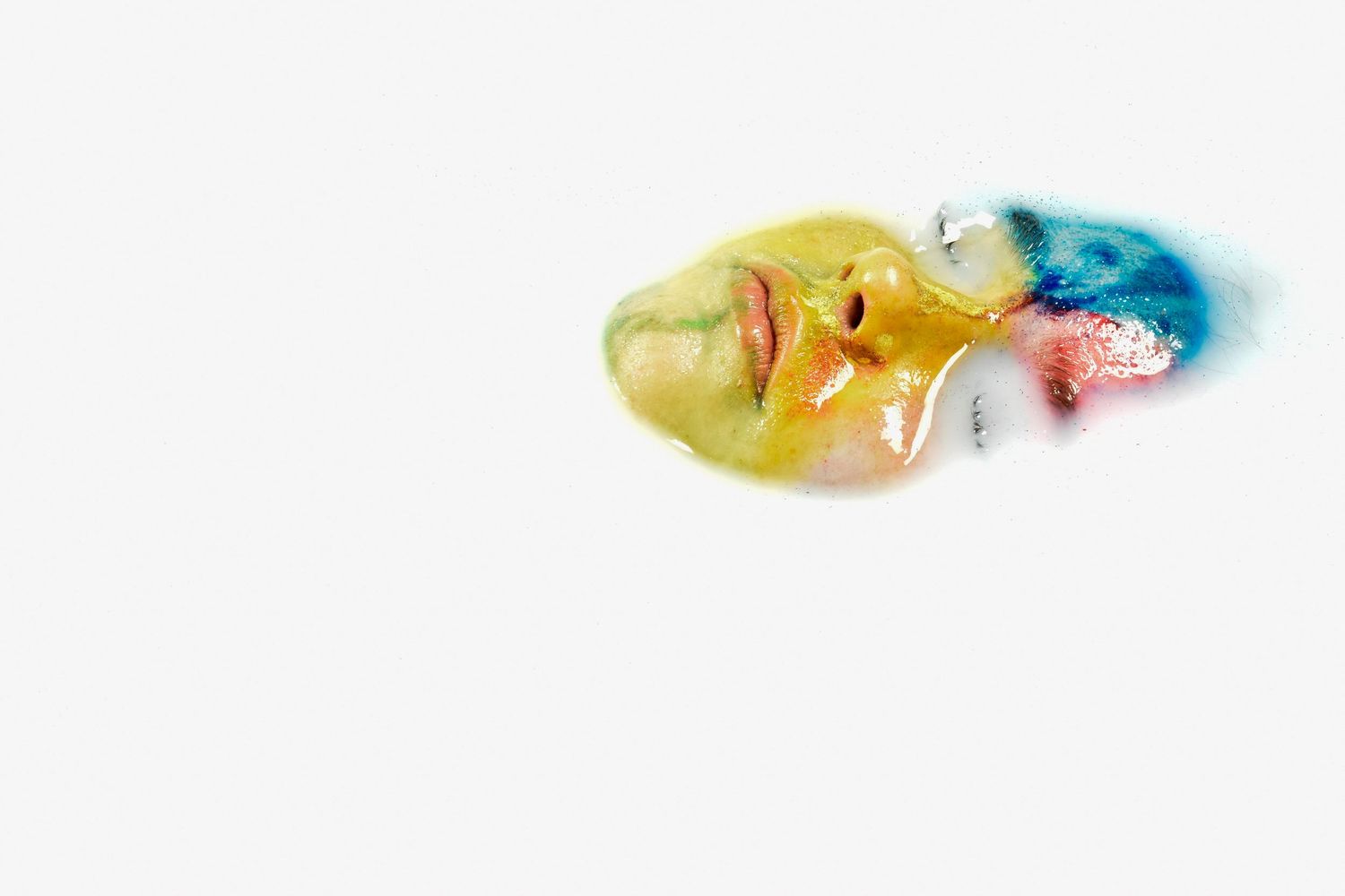 Colorful artistic face sculpture with yellow, blue, and pink paint on white background.