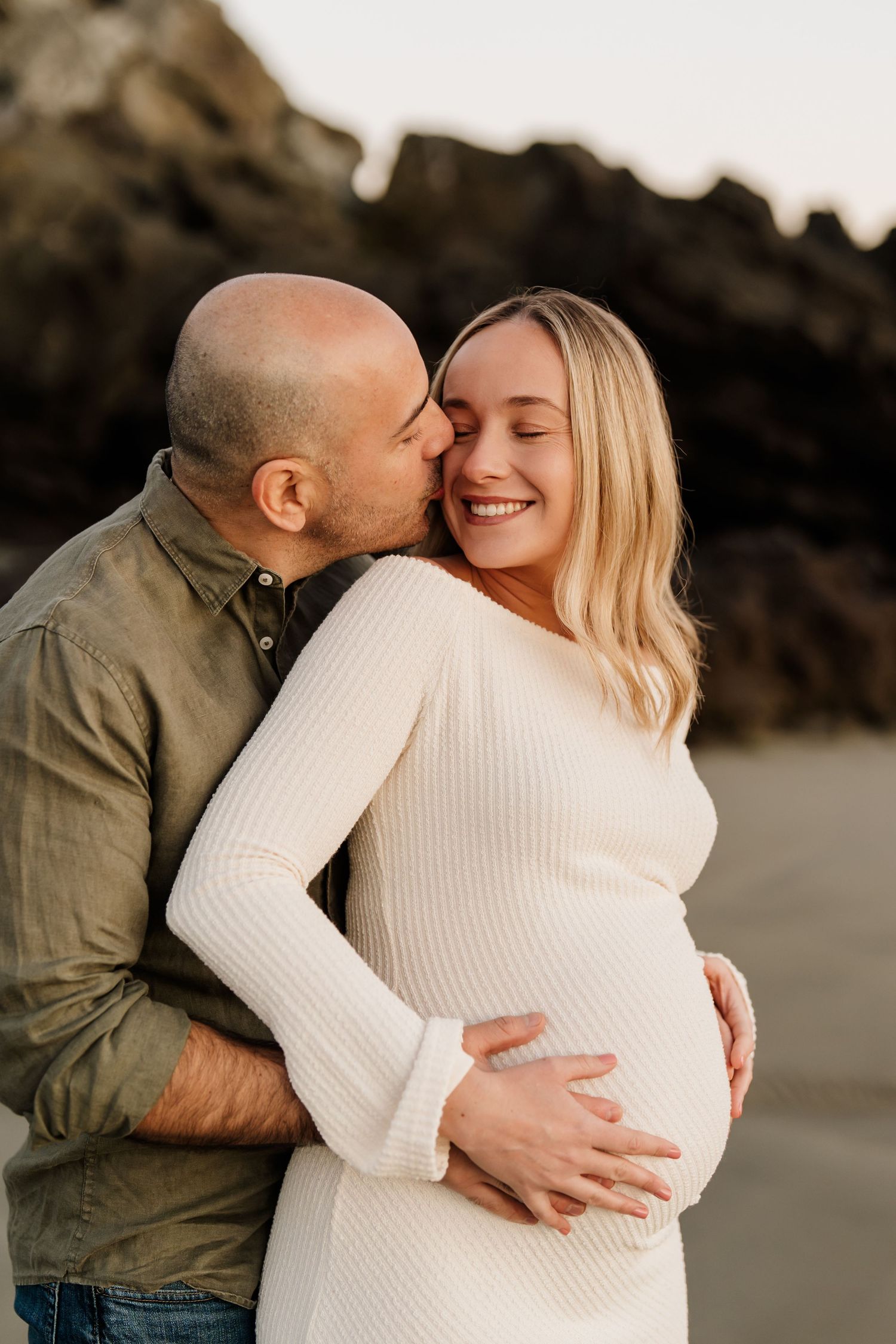 Expectant dad kissing mum as she cradles her baby bump during their Christchurch maternity photoshoot.