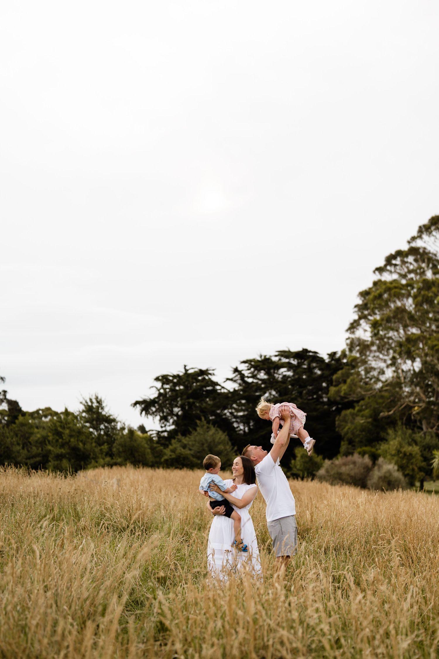 A family playing in a long grassy field in a Christchurch location