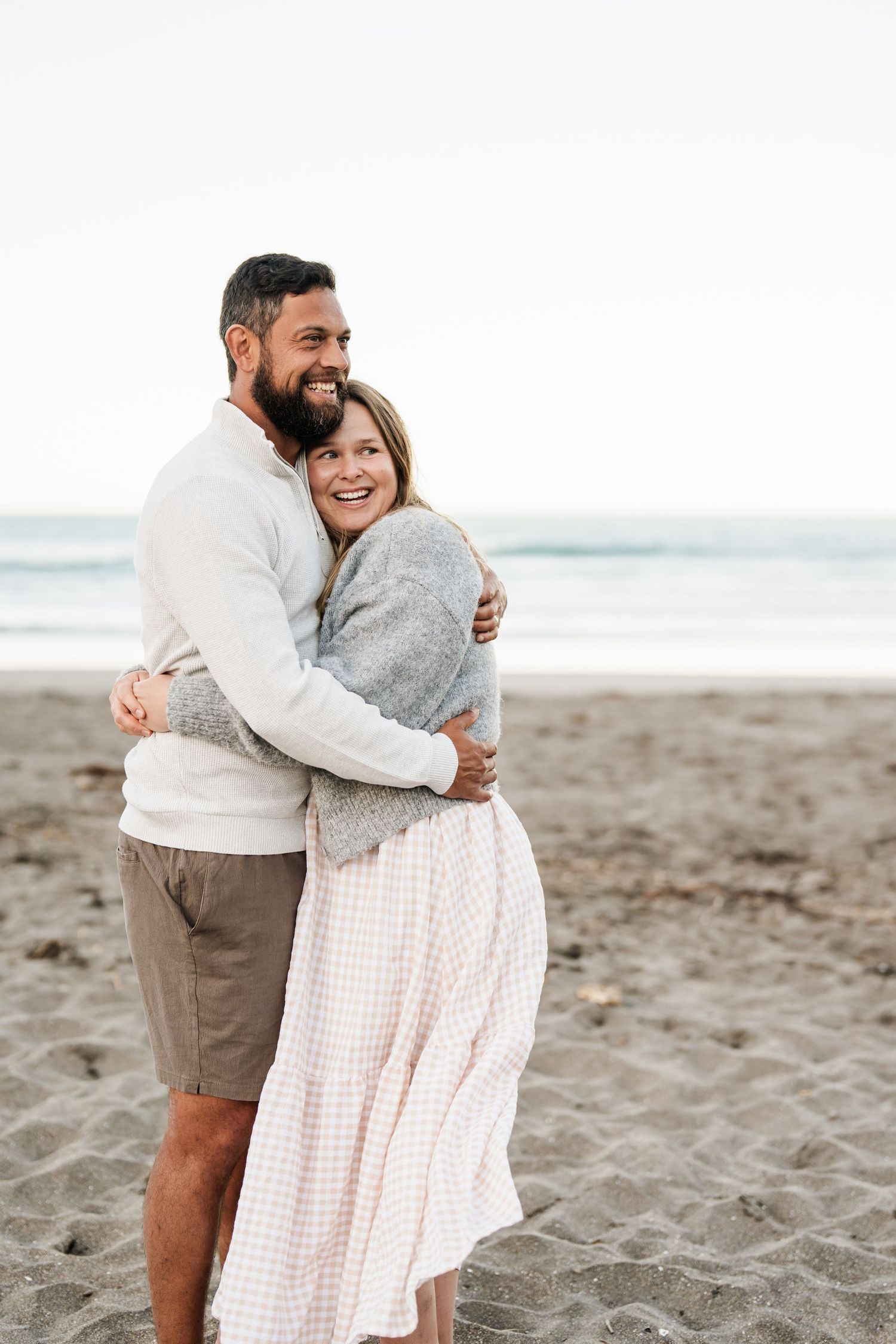 Couple embracing on a Christchurch beach during a relaxed family photography session