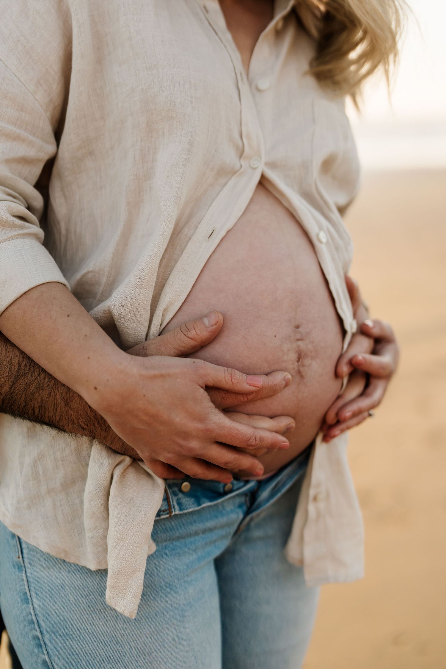 Expecting parents holding a baby bump during an outdoor maternity photography session in Christchurch