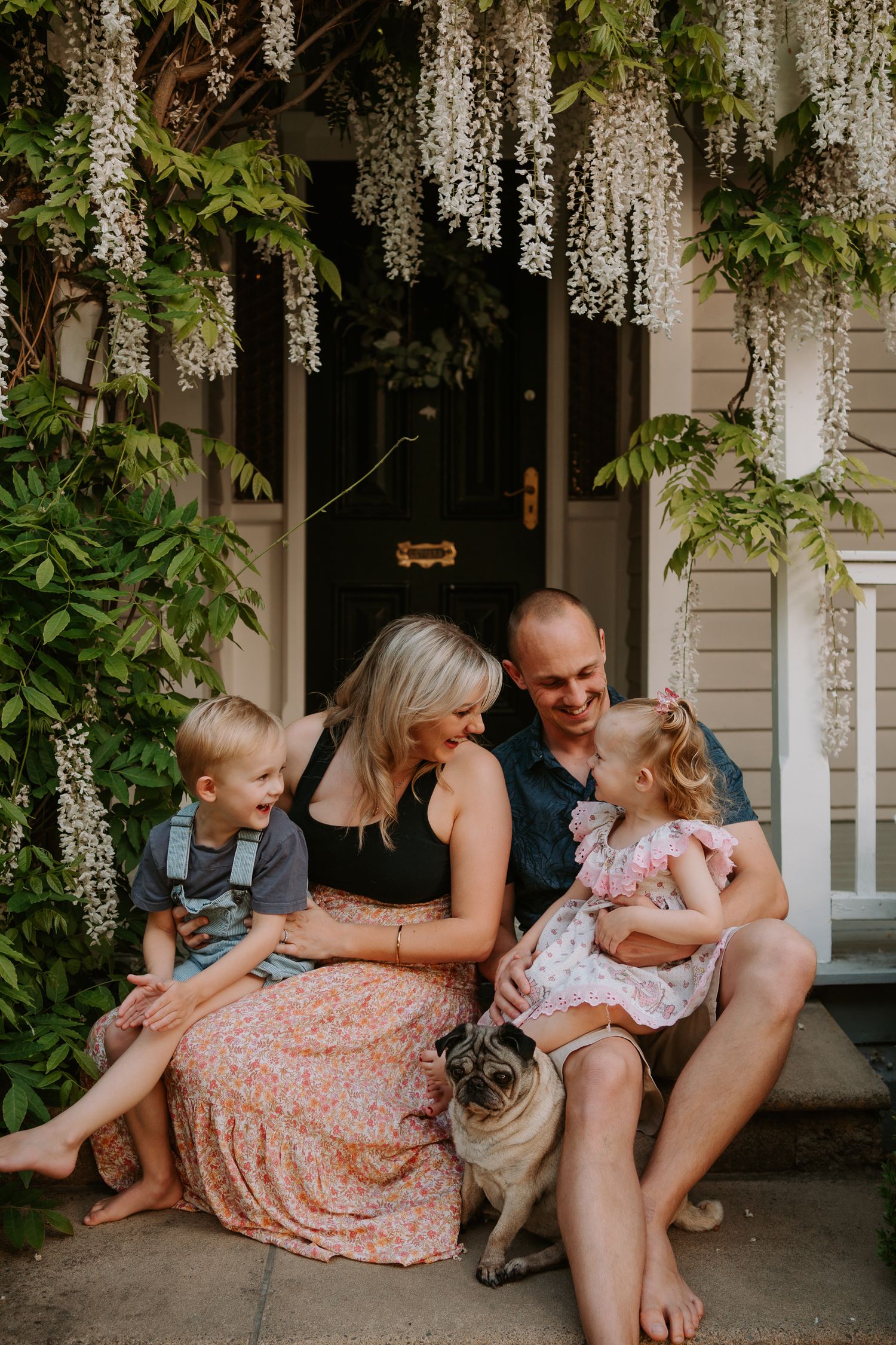 Family of four sitting together outside their home during a relaxed Christchurch family photography session