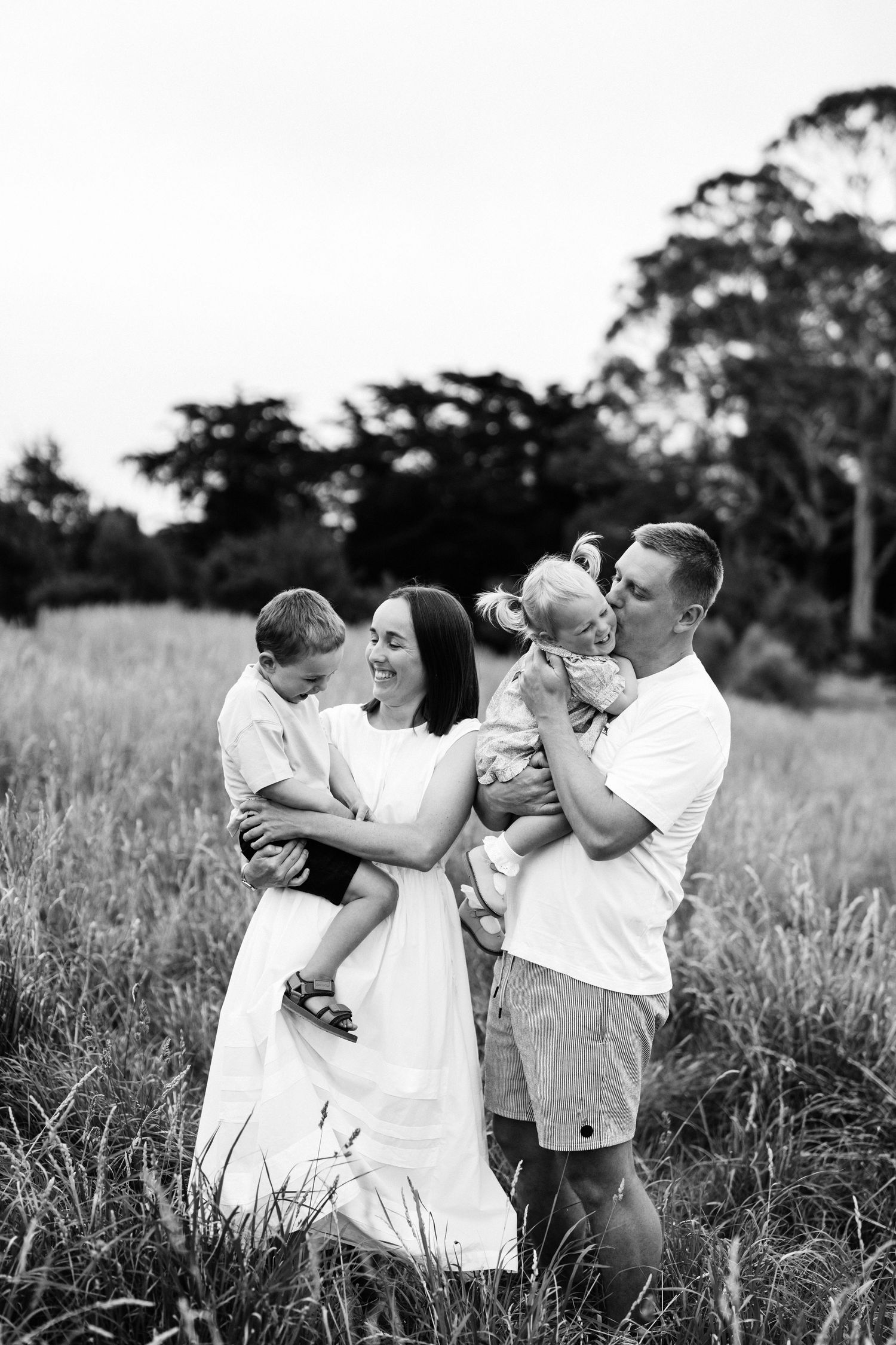 Black and white family photo of parents with their two young children outdoors in Christchurch