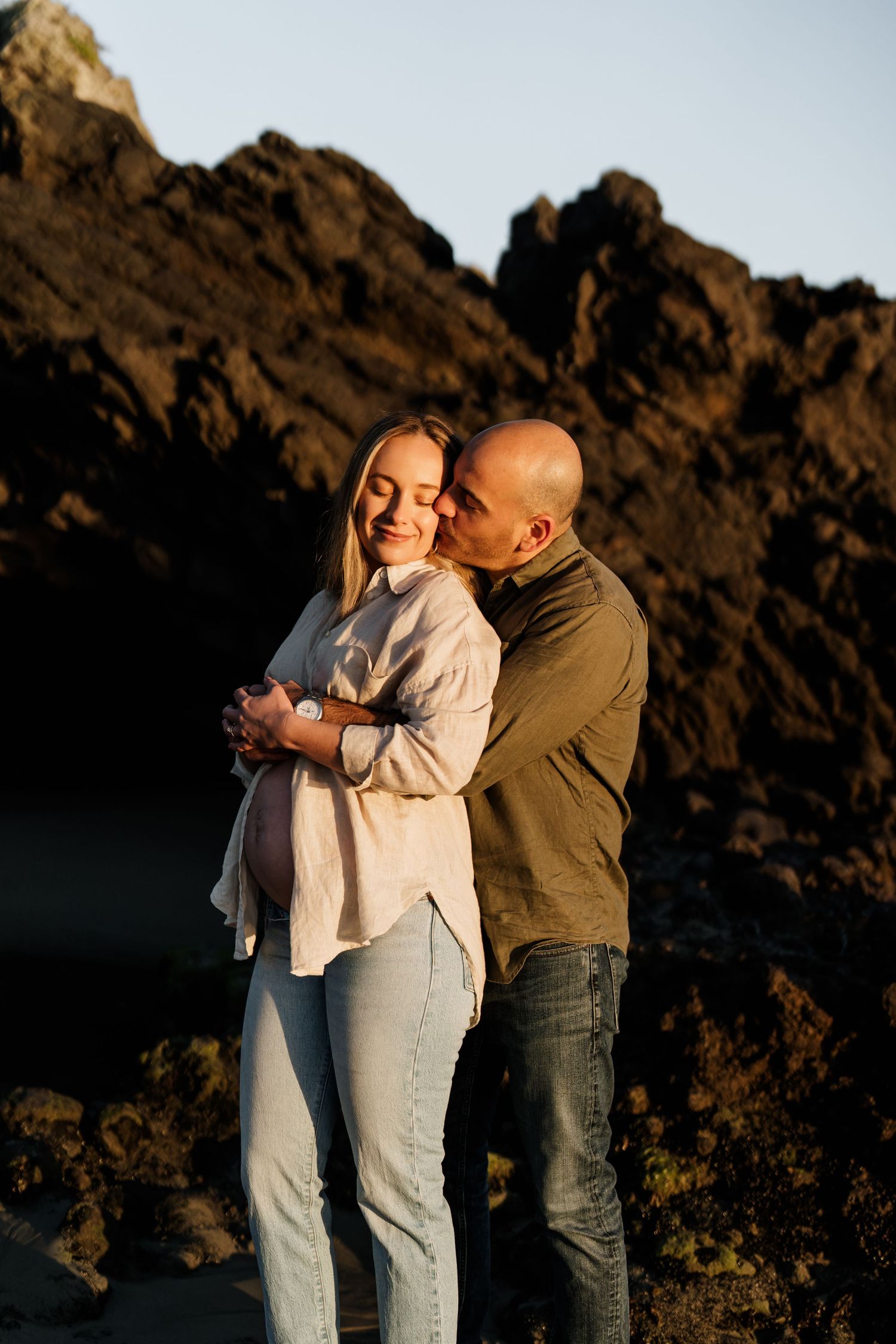 Expectant couple cuddling together during their sunrise maternity session at Sumner Beach in Christchurch.