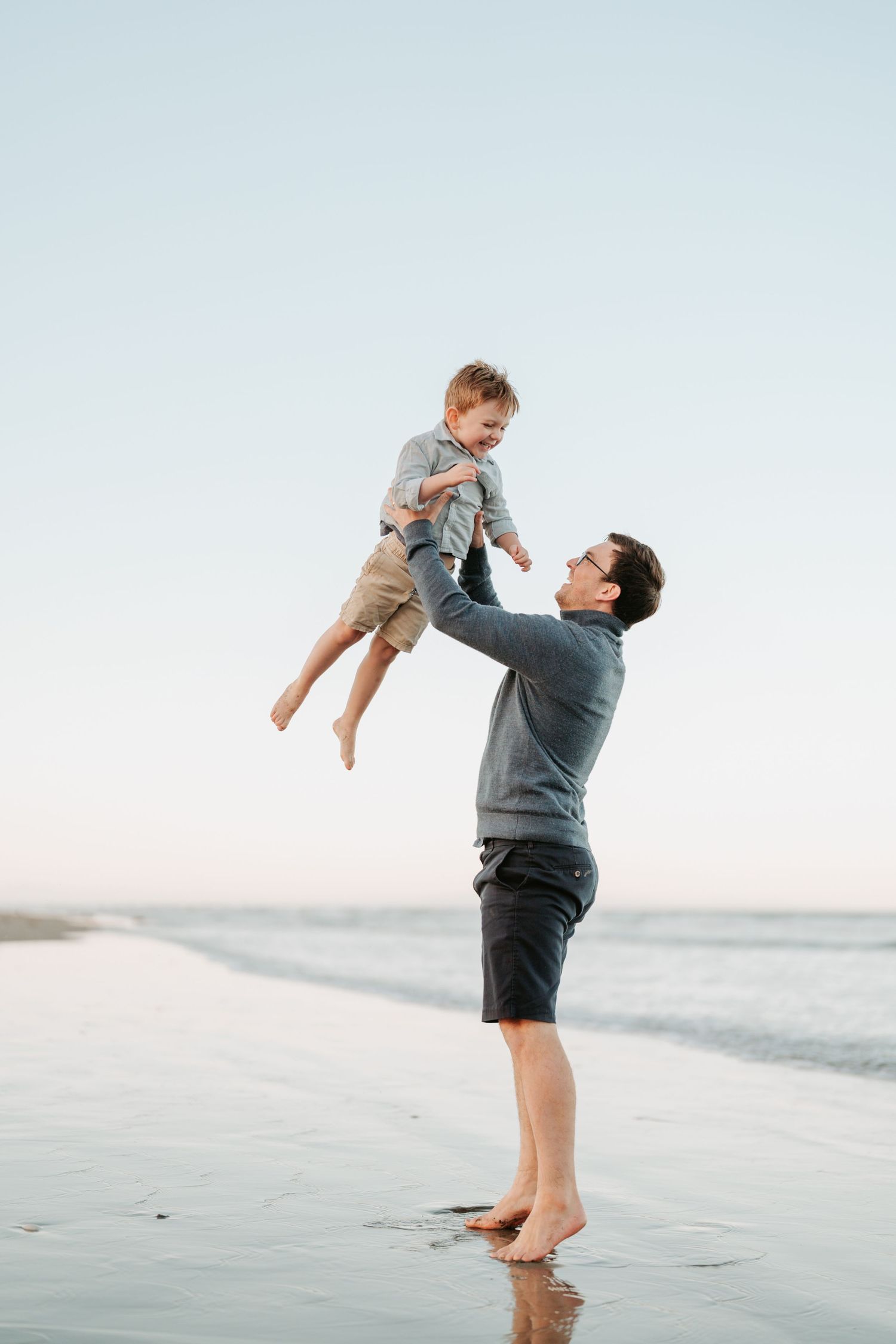 Dad lifting his young child into the air during a Christchurch beach family photography session