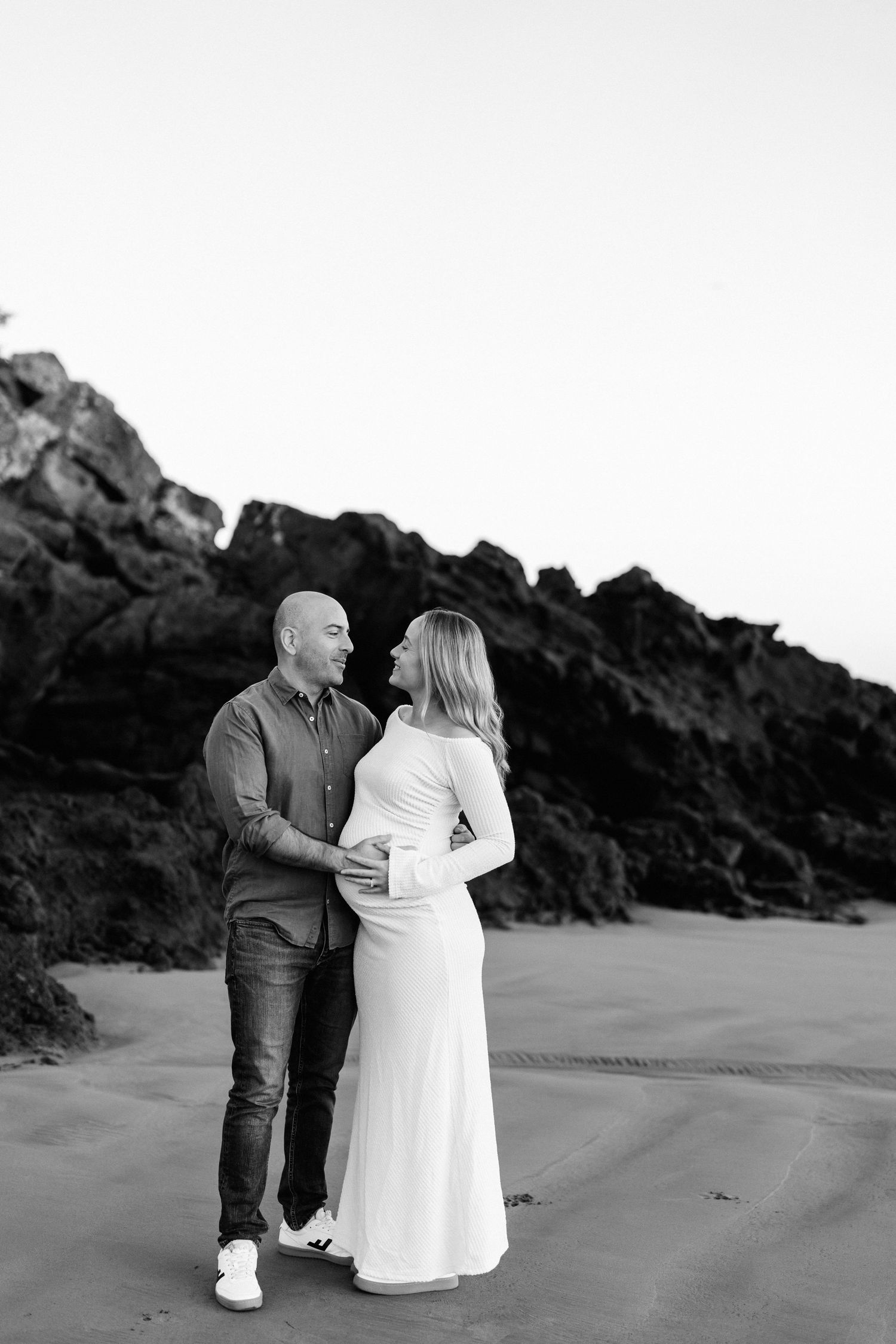 Black and white maternity photo of an expectant couple together on Sumner Beach in Christchurch.