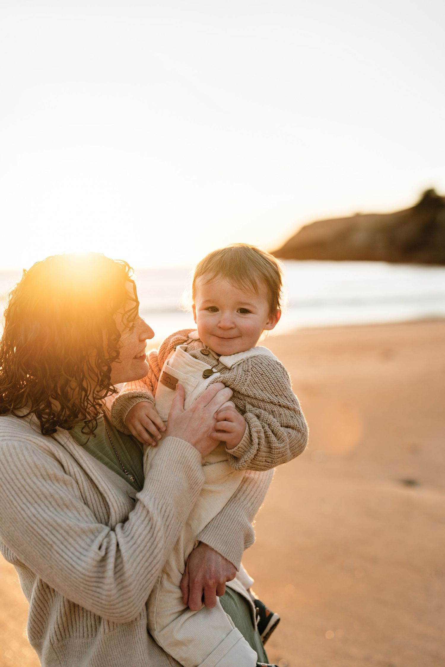 Mum holding her young child at sunset during a relaxed Christchurch beach family photography session