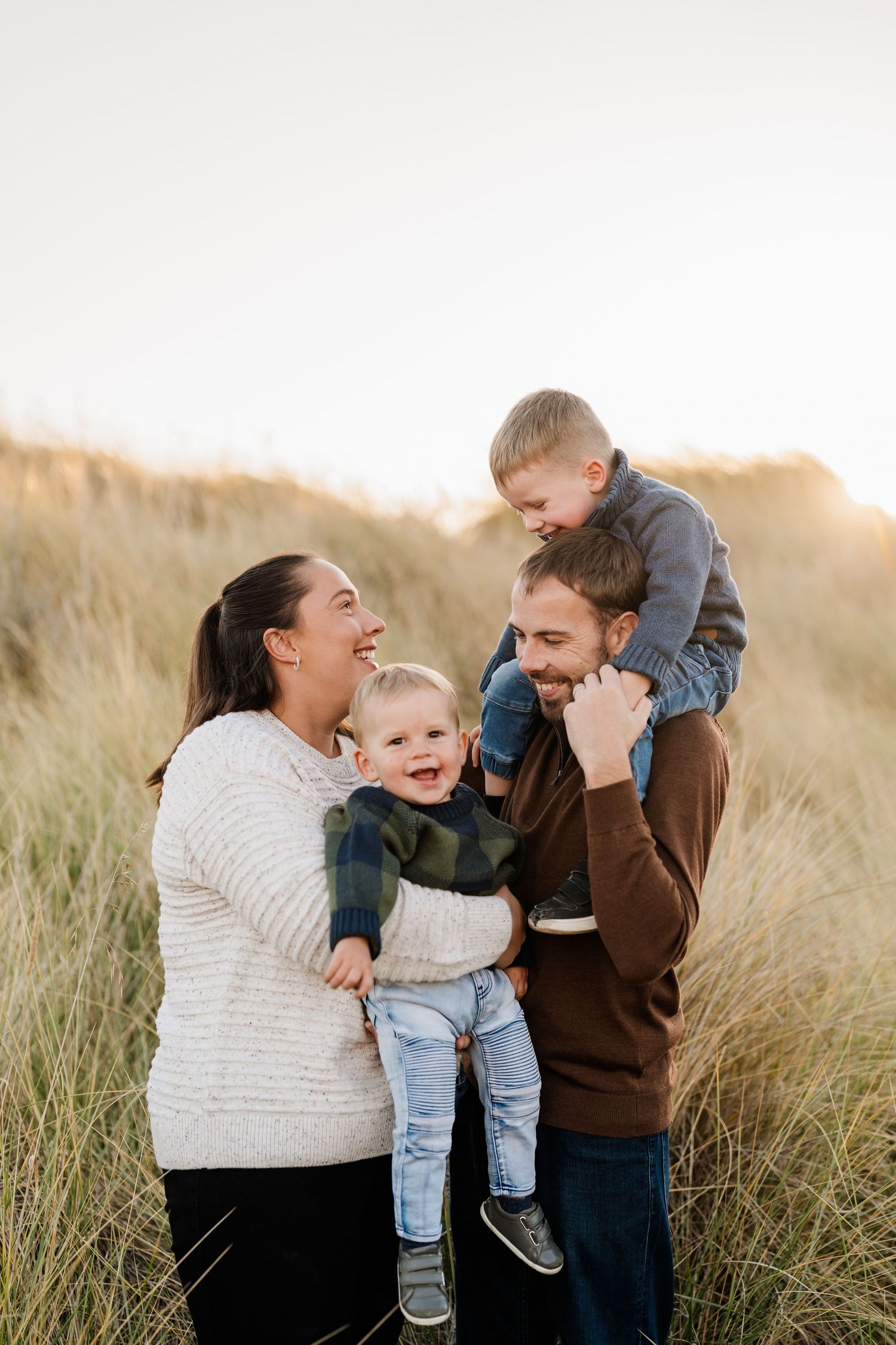 Parents with their two young boys in the sand dunes during an outdoor Christchurch family photography session