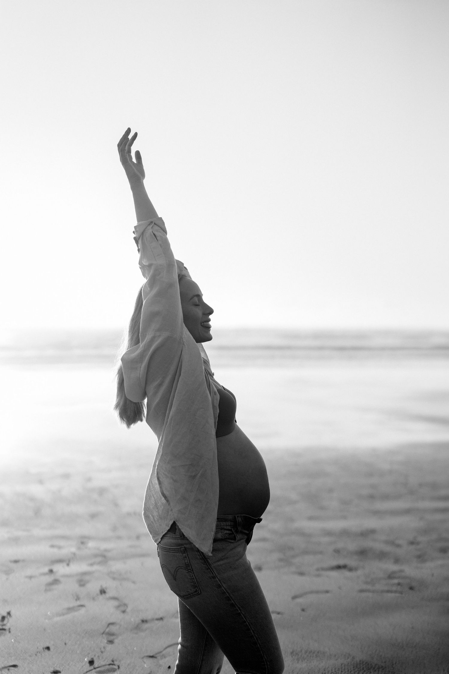 Black and white maternity photo of a pregnant woman on a Christchurch beach