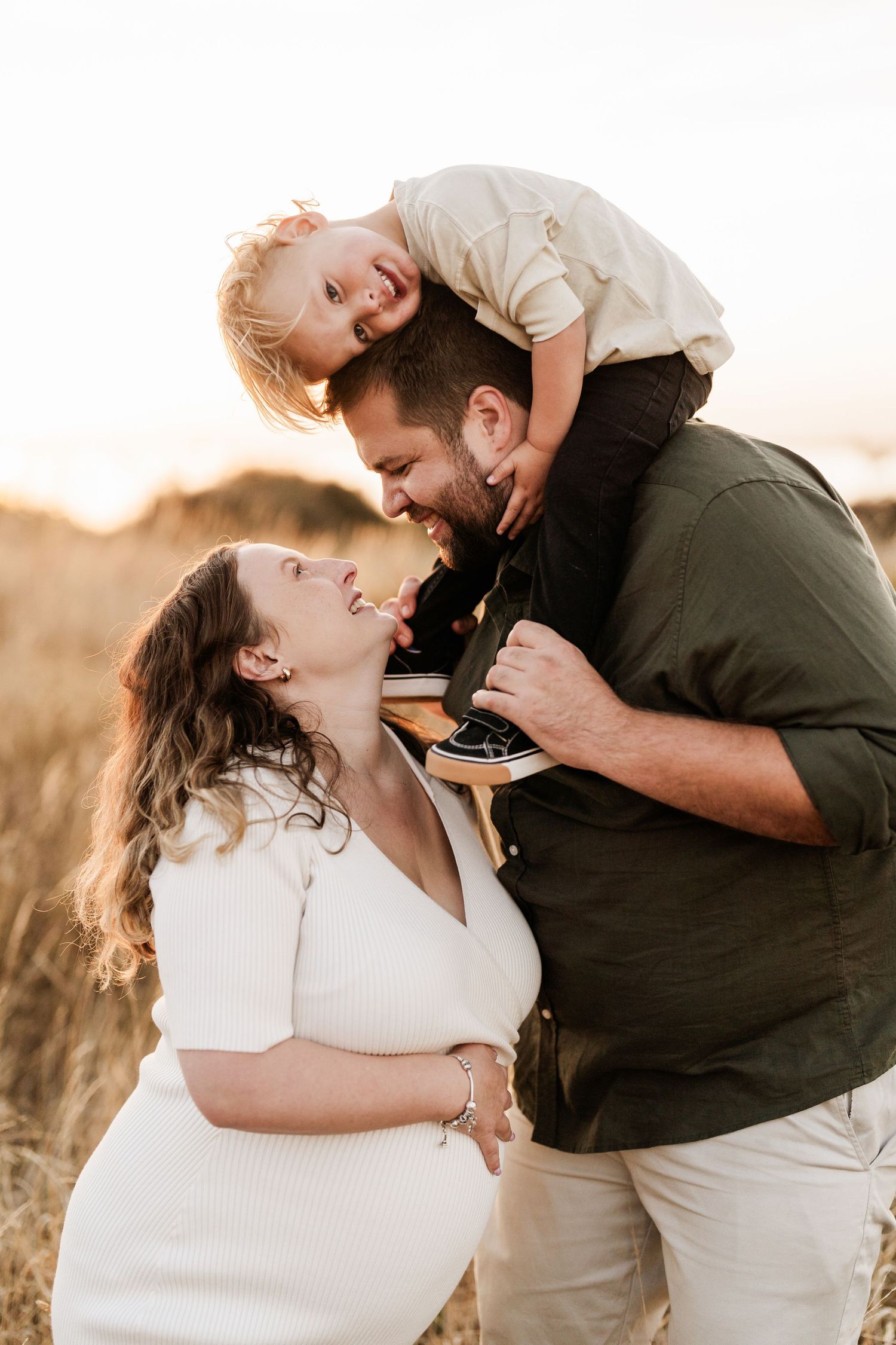 Parents laughing with their young child during a relaxed outdoor maternity photography session in Christchurch