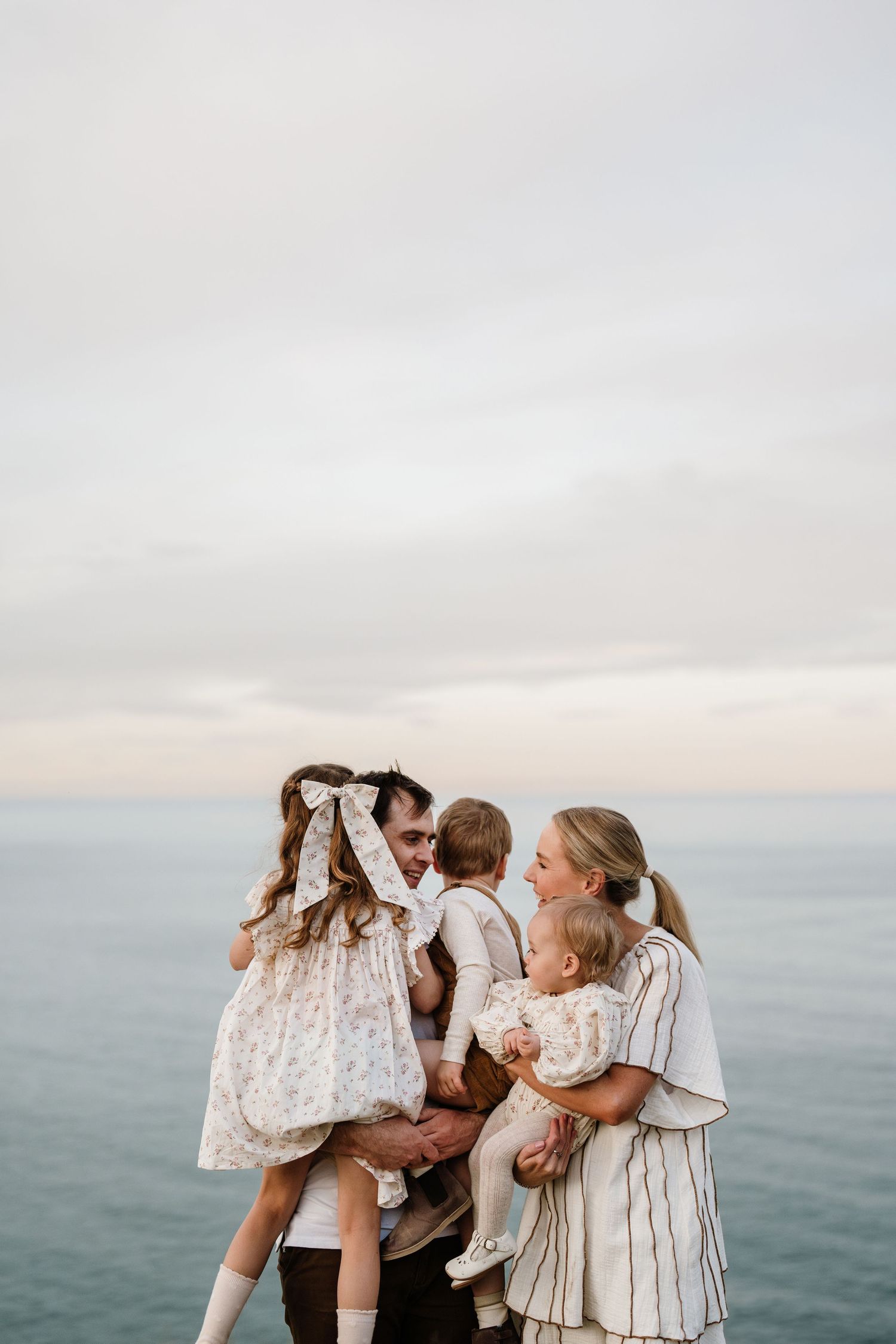 Family cuddling together by the water during a relaxed outdoor family photography session in Christchurch