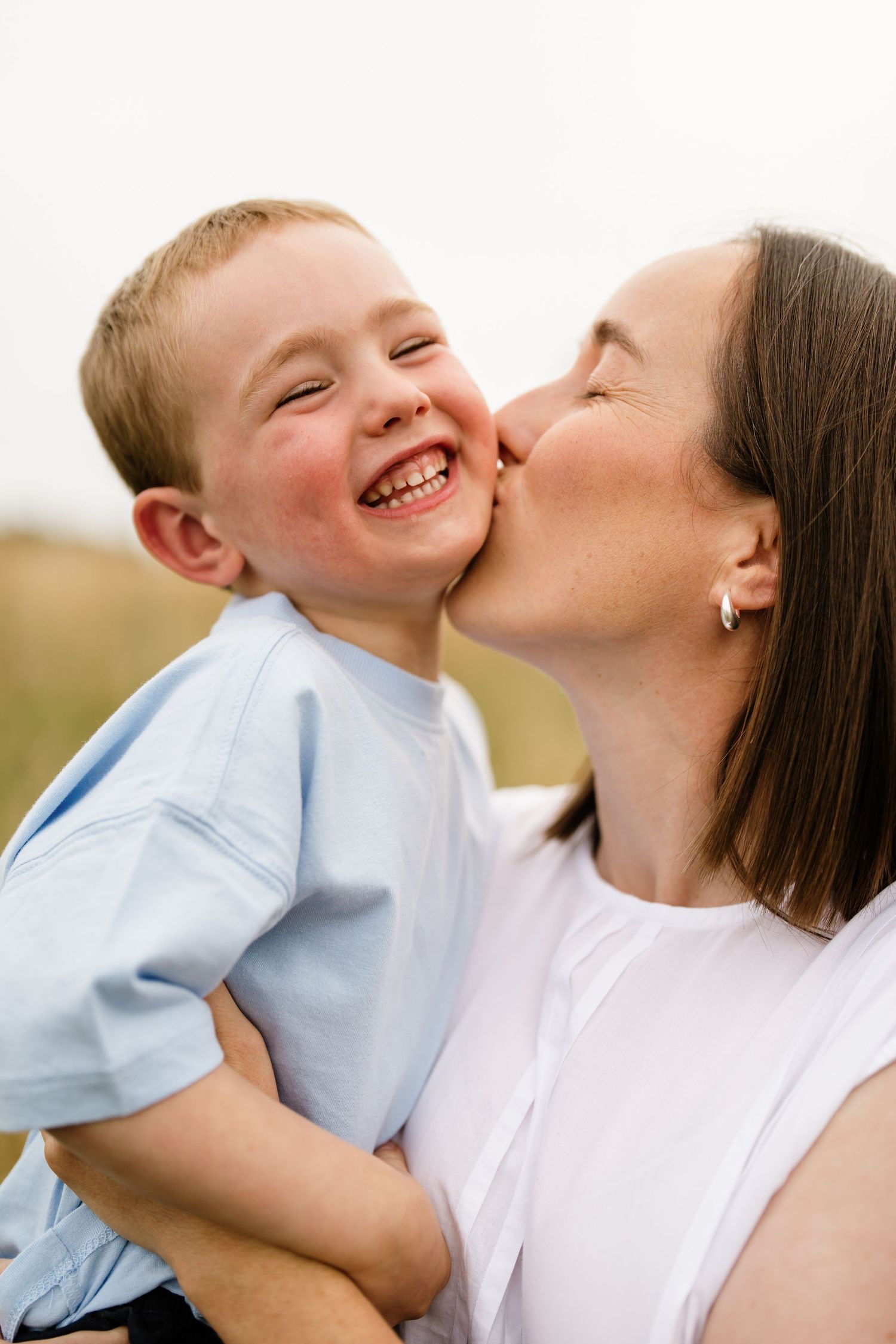 Mum kissing her laughing young son during a natural Christchurch family photo session