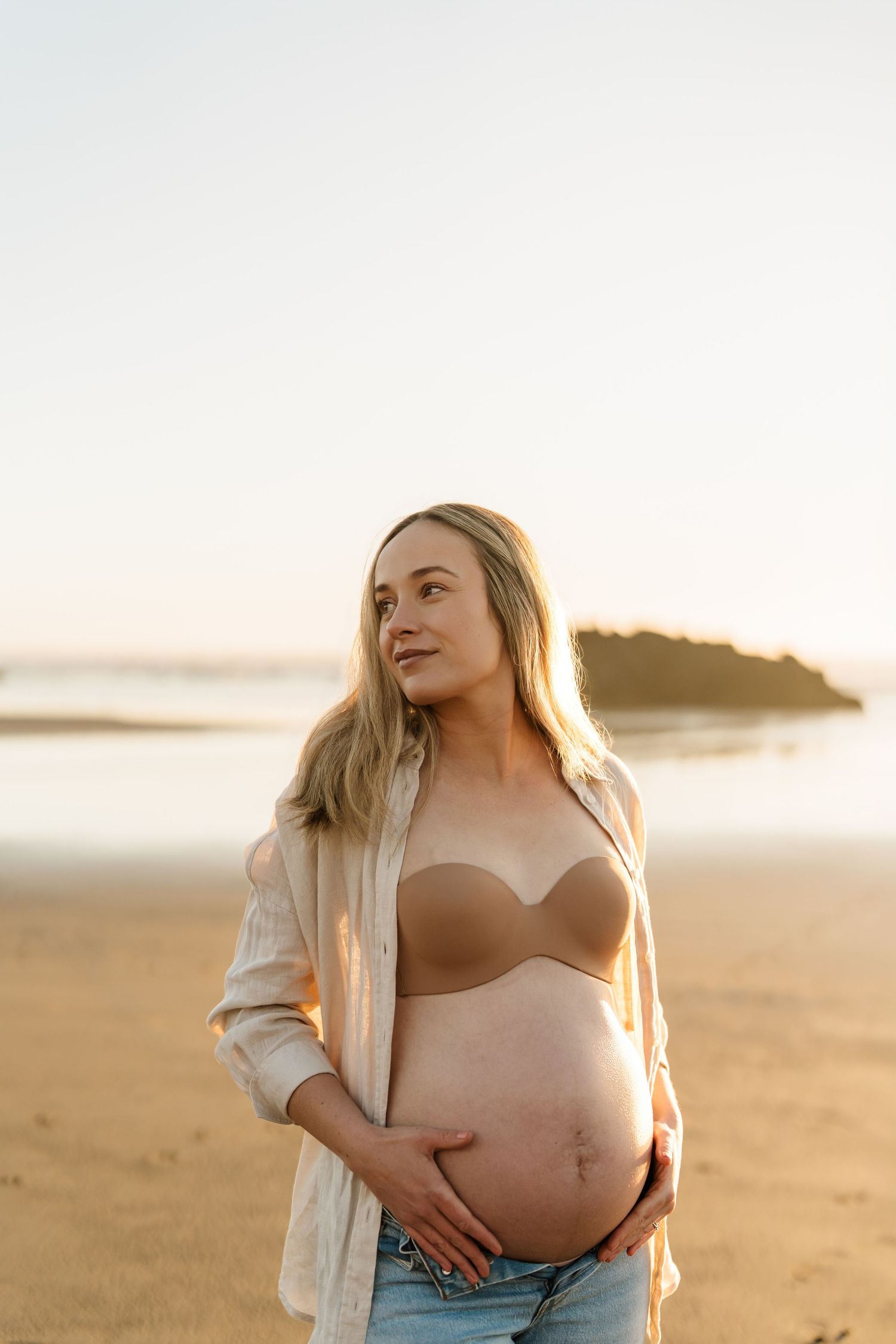 A Canterbury woman showing off her bare baby bump at a sunrise beach session