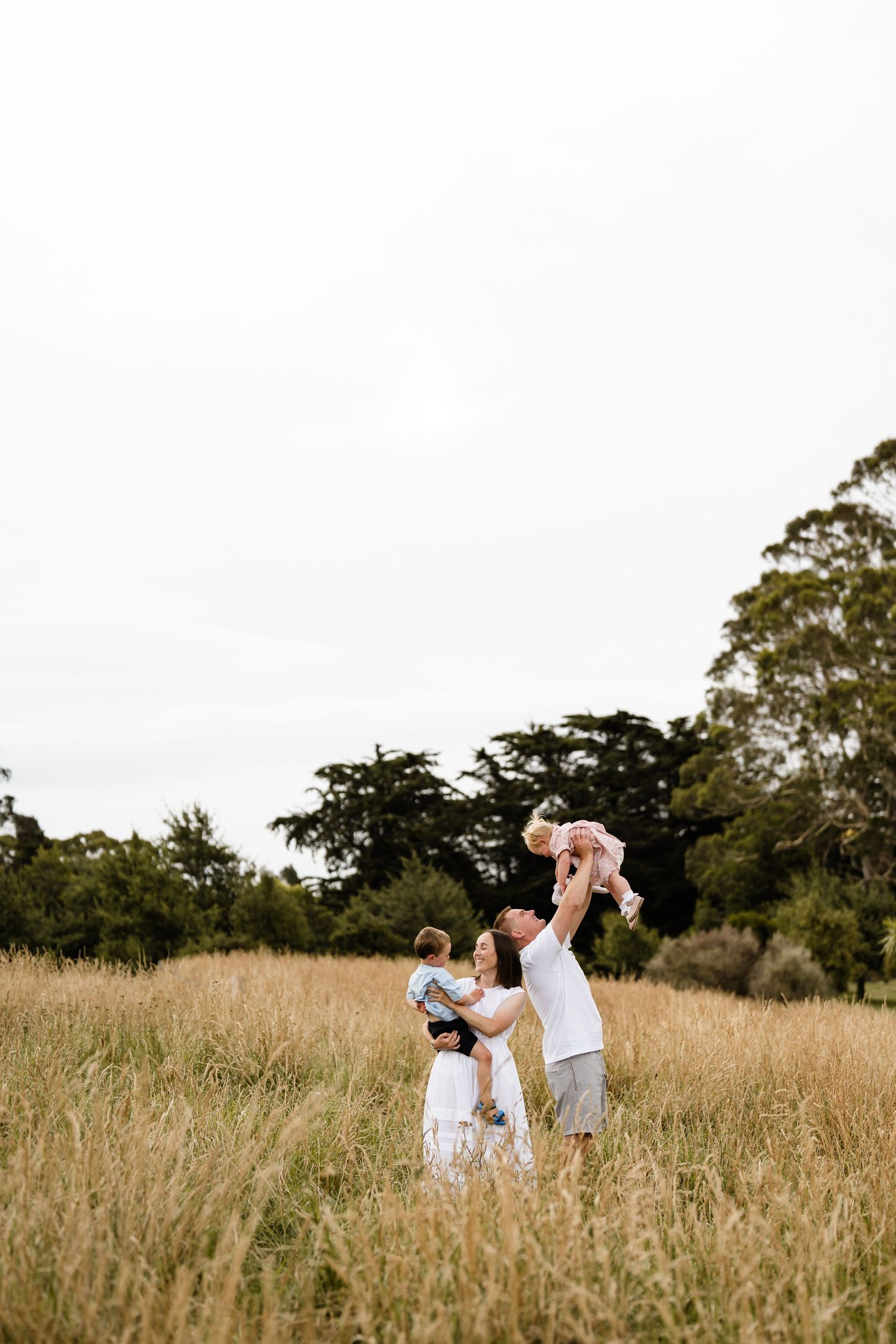 Parents playing with their children in a grassy field during a relaxed Christchurch family photography session