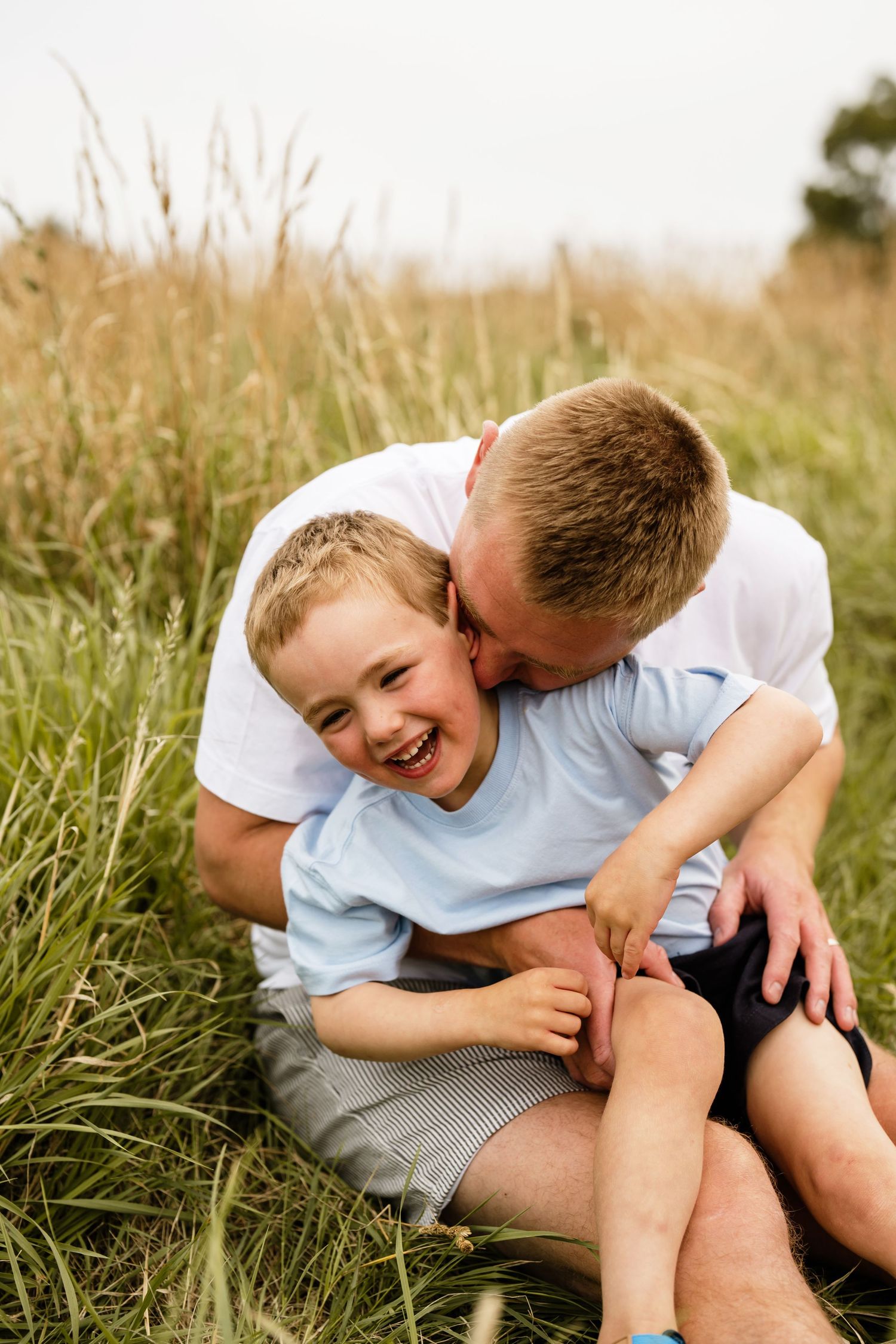 A boy and his dad smiling and playing at a family portrait session