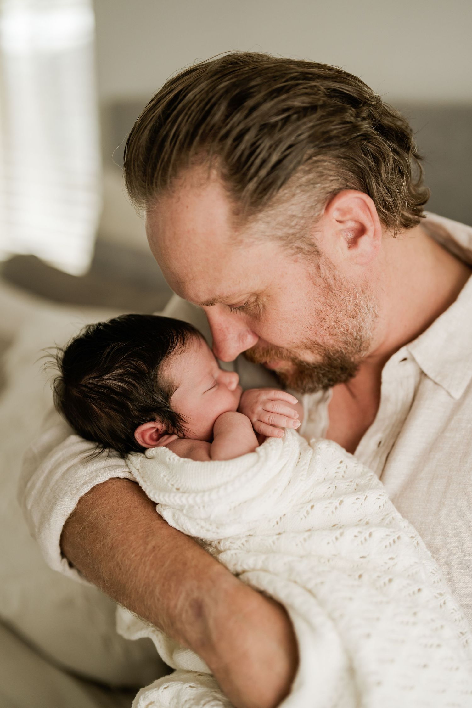 Dad cuddling his newborn baby during a natural Christchurch newborn photography session at home