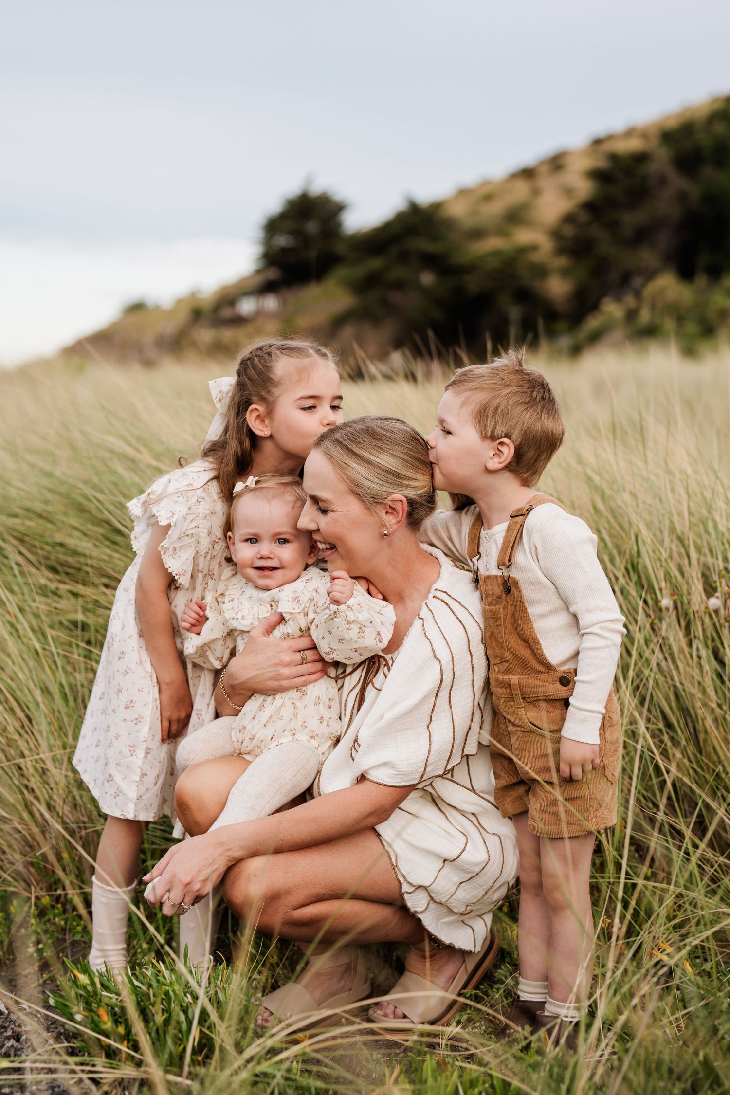 Mum cuddling her three children in long grass during a natural Christchurch family photo session