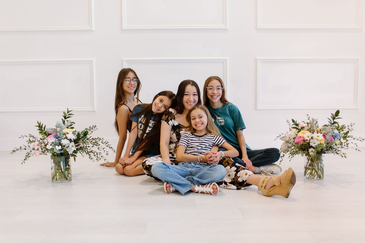 A group relaxes together on a white floor with delicate floral arrangements visible in the background.