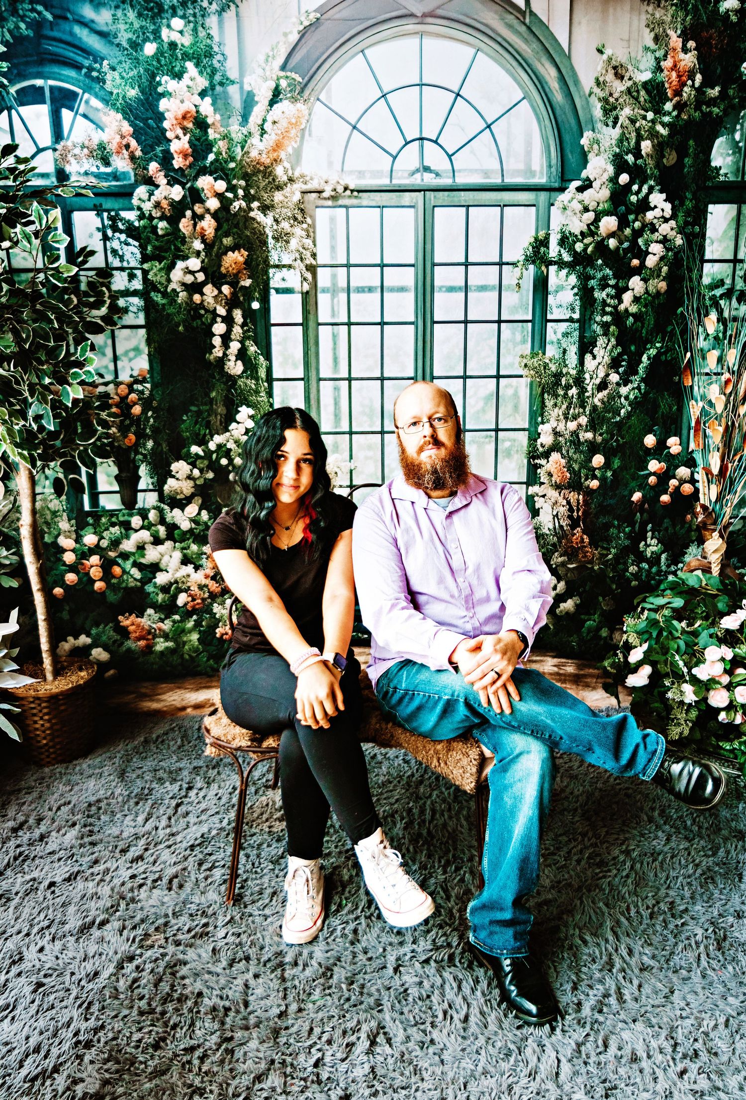 A couple sits together in a romantic garden setting with arched windows and climbing roses in a series of photos.