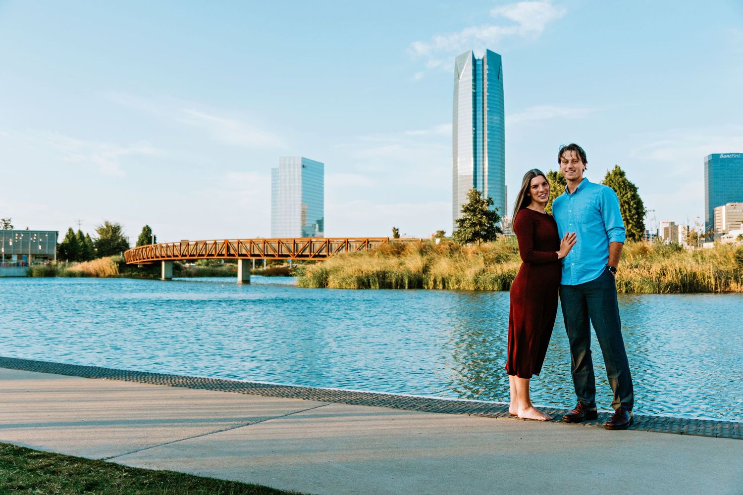 A couple walks along the Chicago lakefront with the skyline and Lake Michigan in the background.
