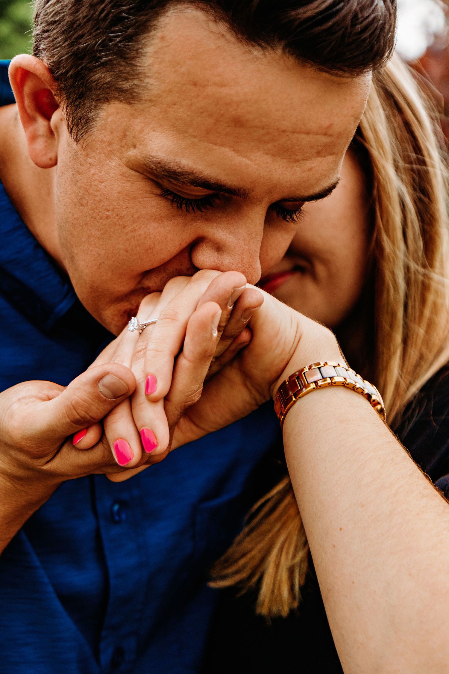 A series of intimate close-up shots showing someone kissing another person's hand with pink nail polish against a dark background.