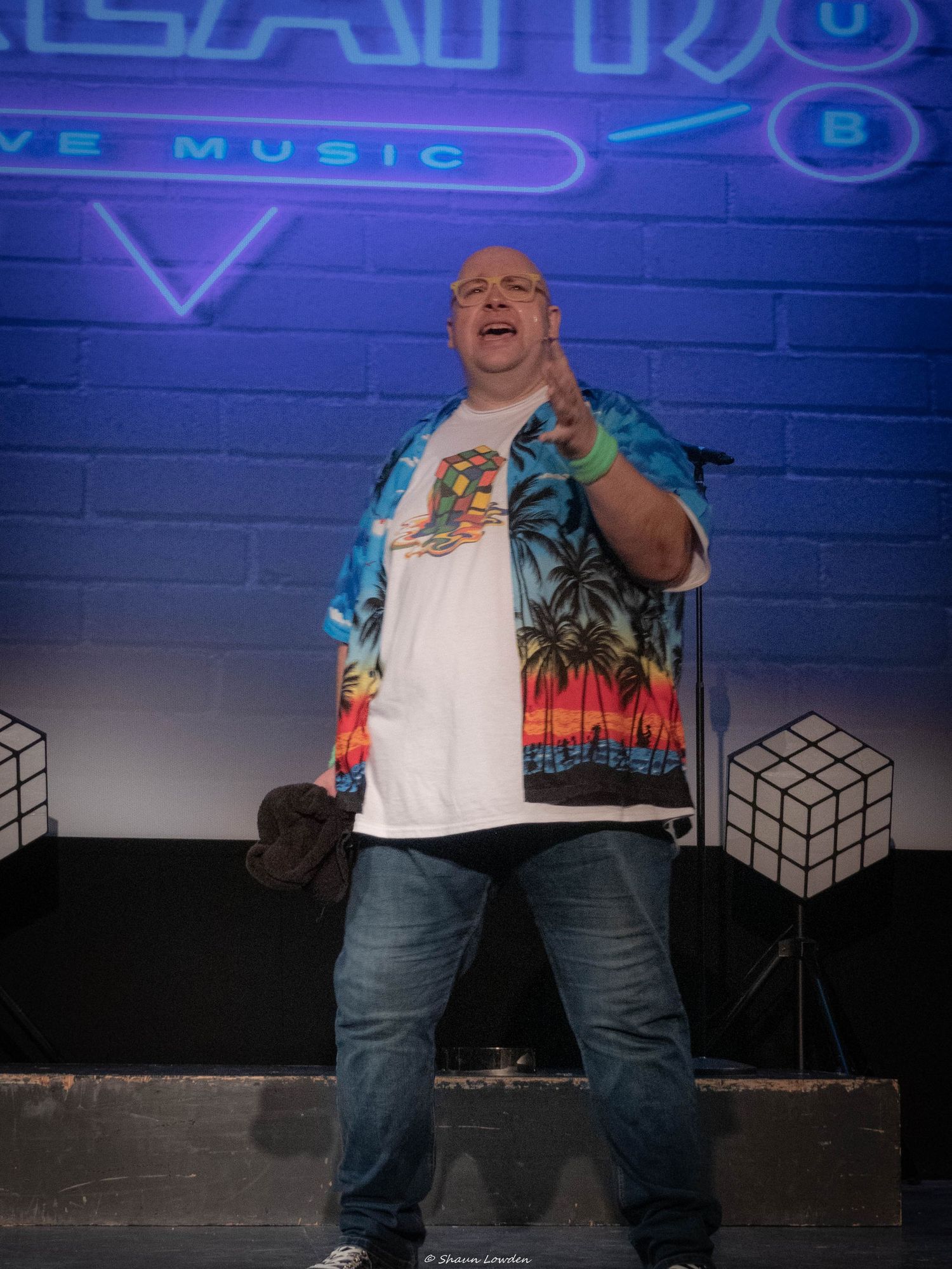A theatrical performance with neon signage and dramatic stage lighting.