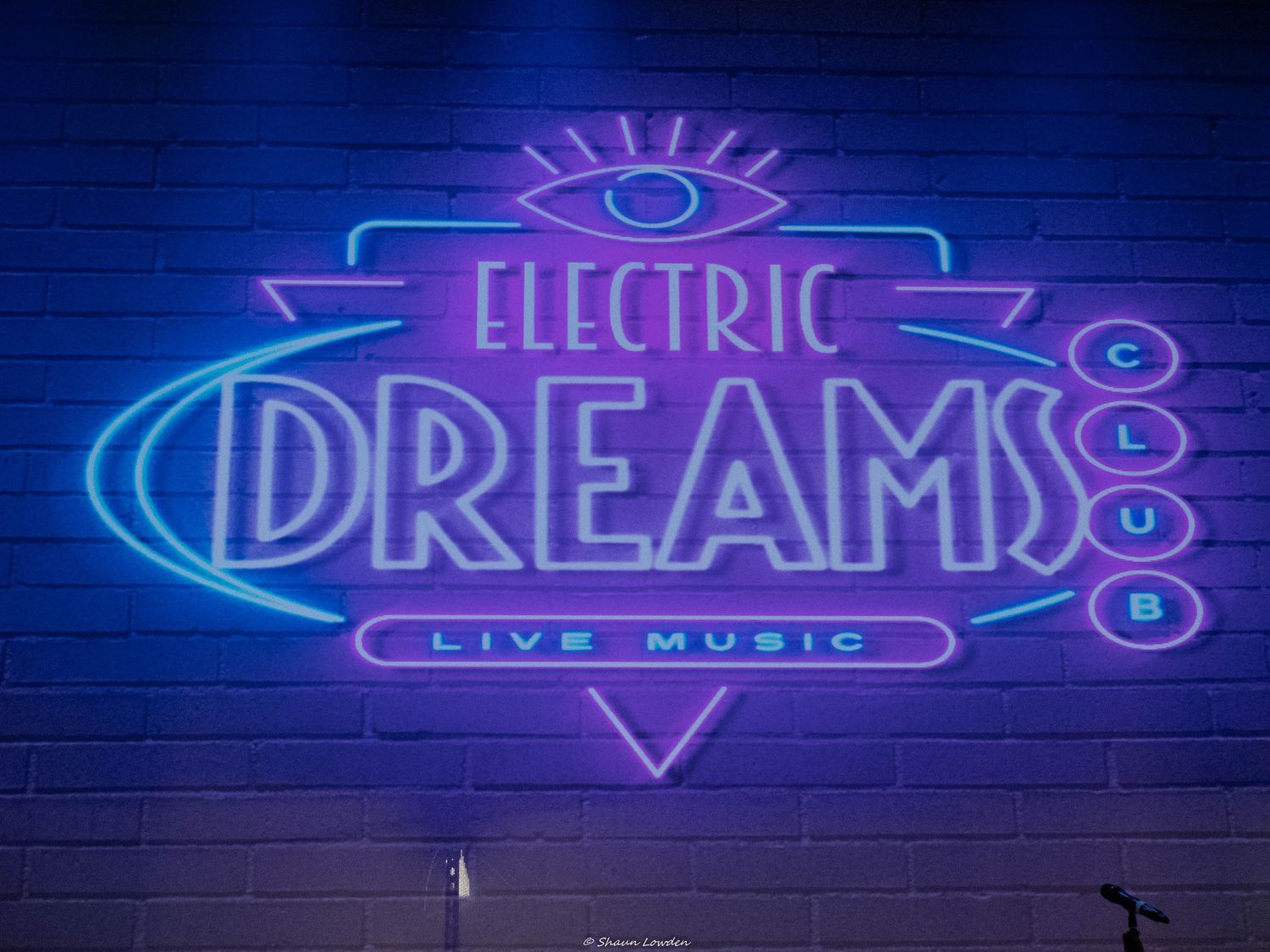 Neon sign reading 'Electric Dreams Live Music' in purple and blue illuminated lettering.