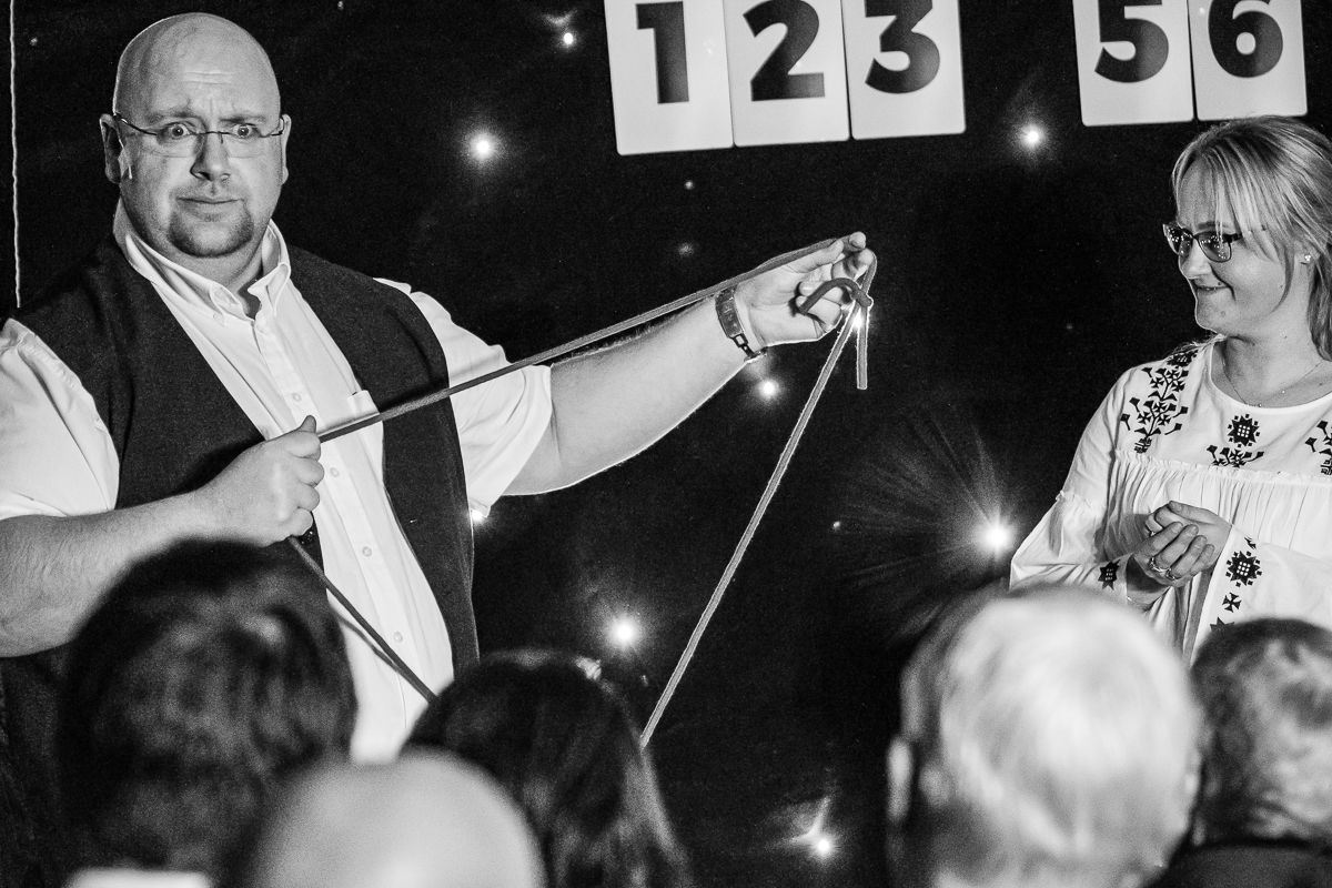 A magician performs a rope trick on stage with a female assistant before a live audience.