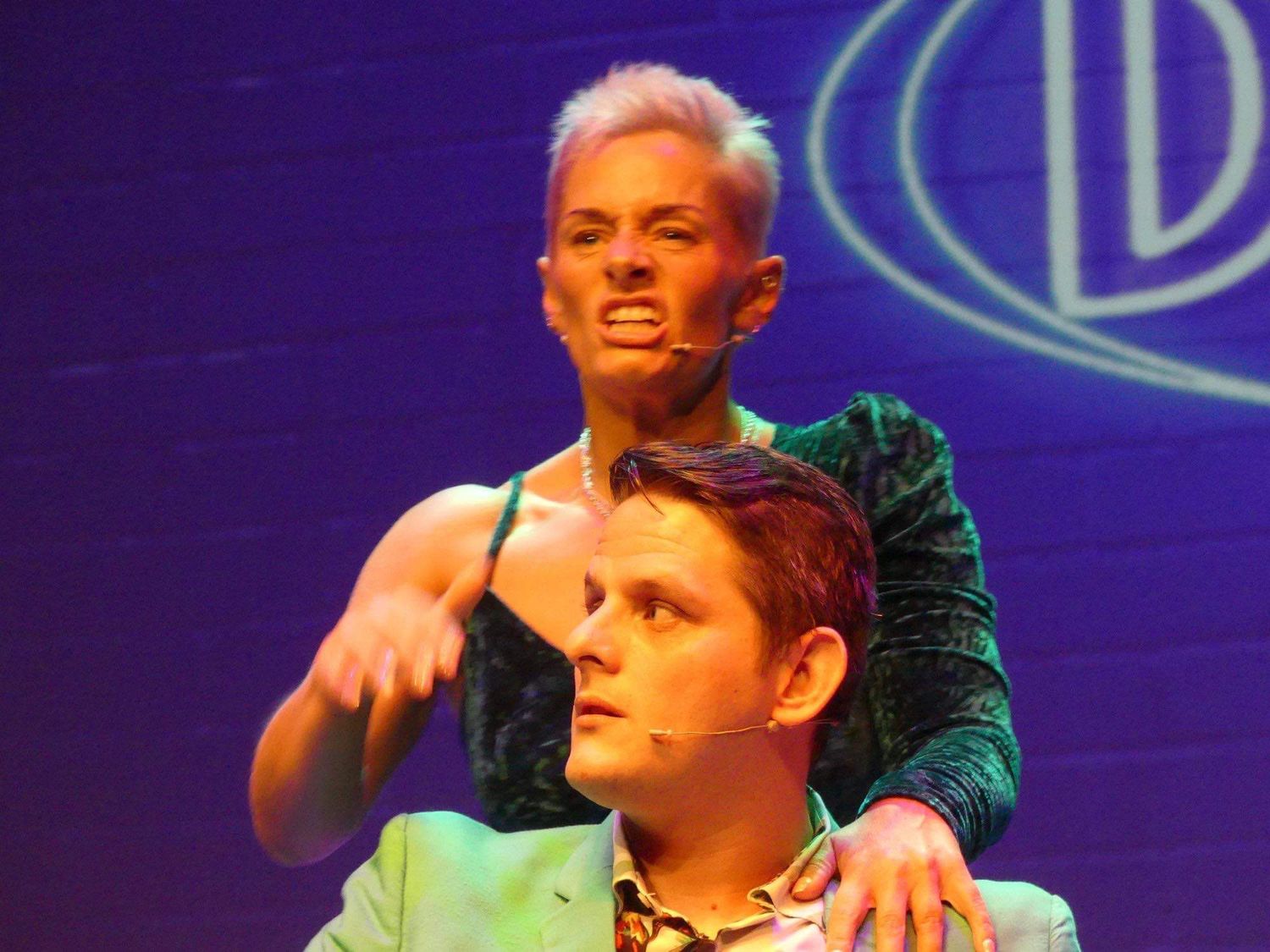 Stage performance captured under purple lighting with dramatic gestures.